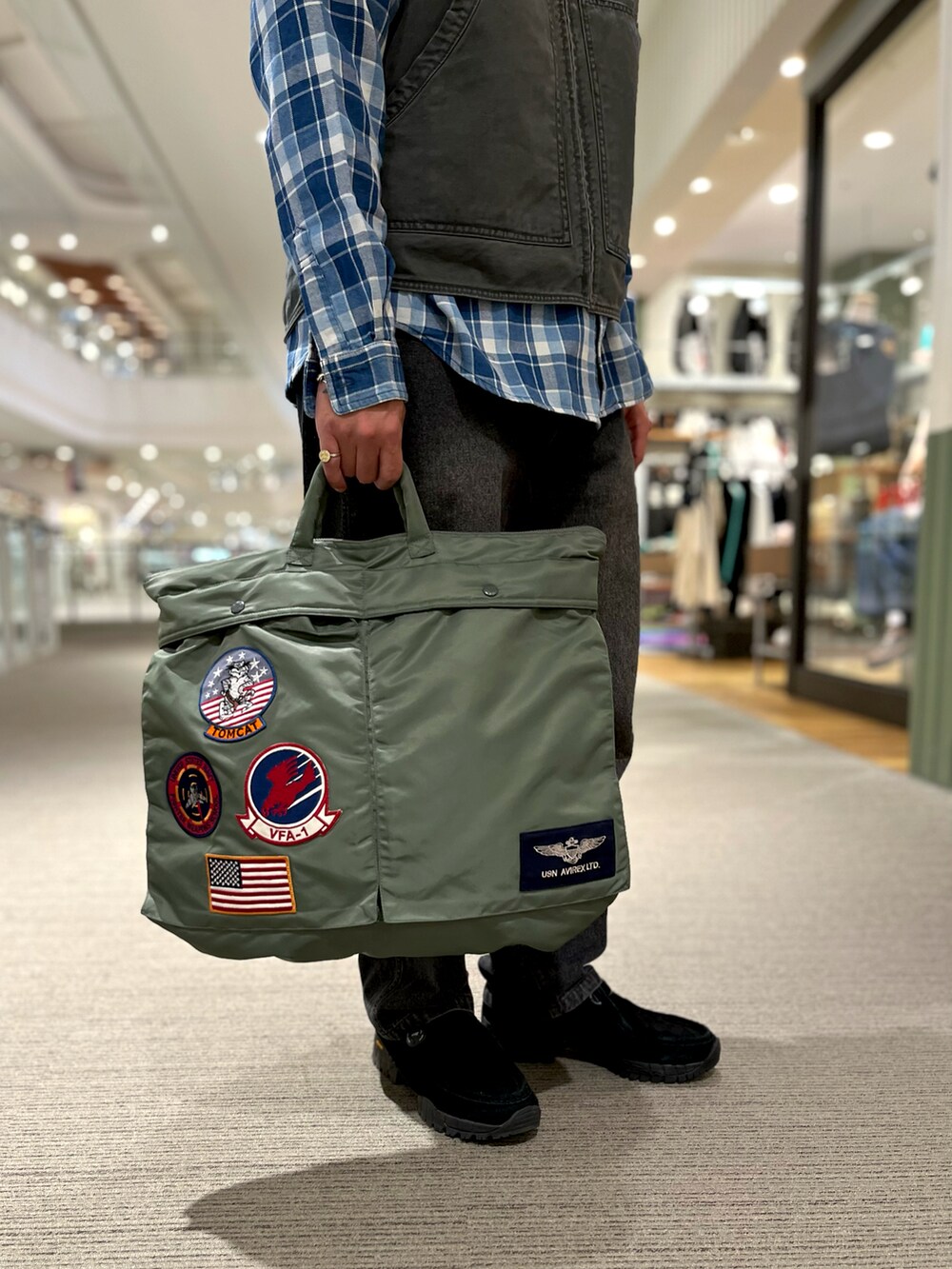 オレンジ系のシャツ/ブラウス、グリーン系のトートバッグ、ブラック系のベストを着用したメンズの冬コーディネートの3枚目の写真