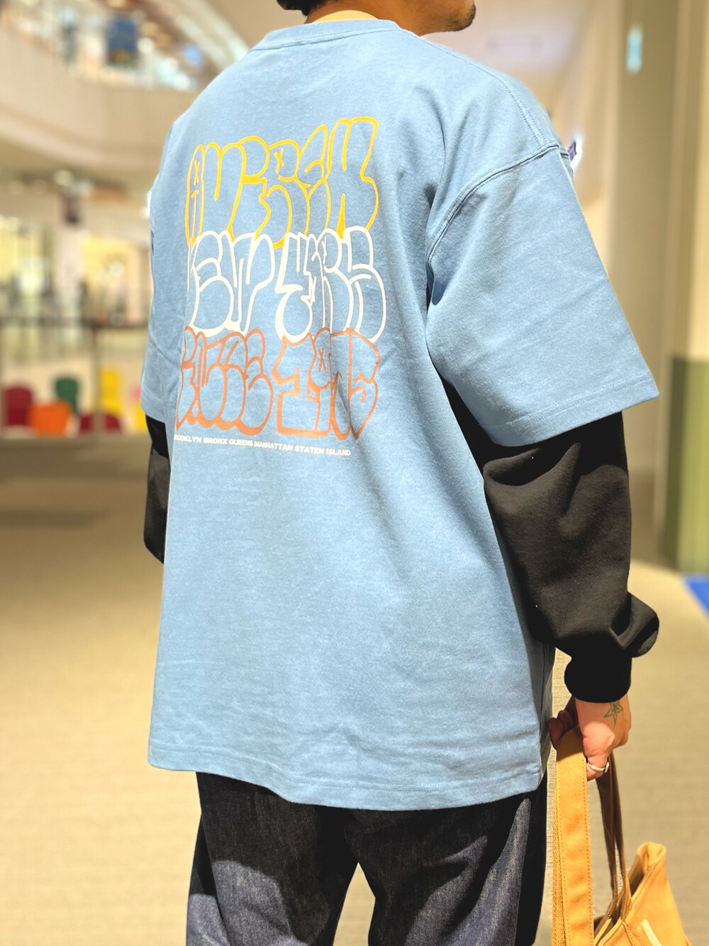 ブラウン系のトートバッグ、グレー系のTシャツ/カットソー、グリーン系のハットを着用したメンズの夏コーディネートの4枚目の写真