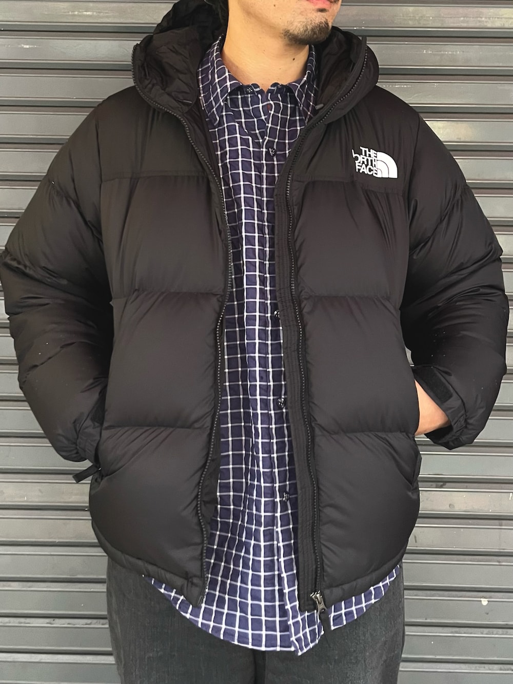 ブラック系のダウンジャケット/コート、ブラック系のデニムパンツ、ブルー系のシャツ/ブラウスを着用したメンズの秋コーディネートの2枚目の写真