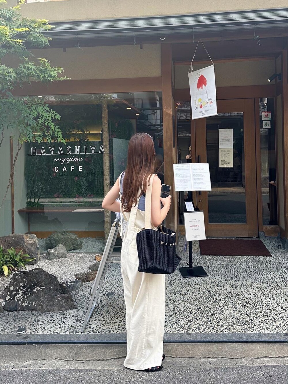 ブルー系のタンクトップ、ホワイト系のサロペット/オーバーオール、ブラック系のサンダルを着用したレディースの秋コーディネートの2枚目の写真