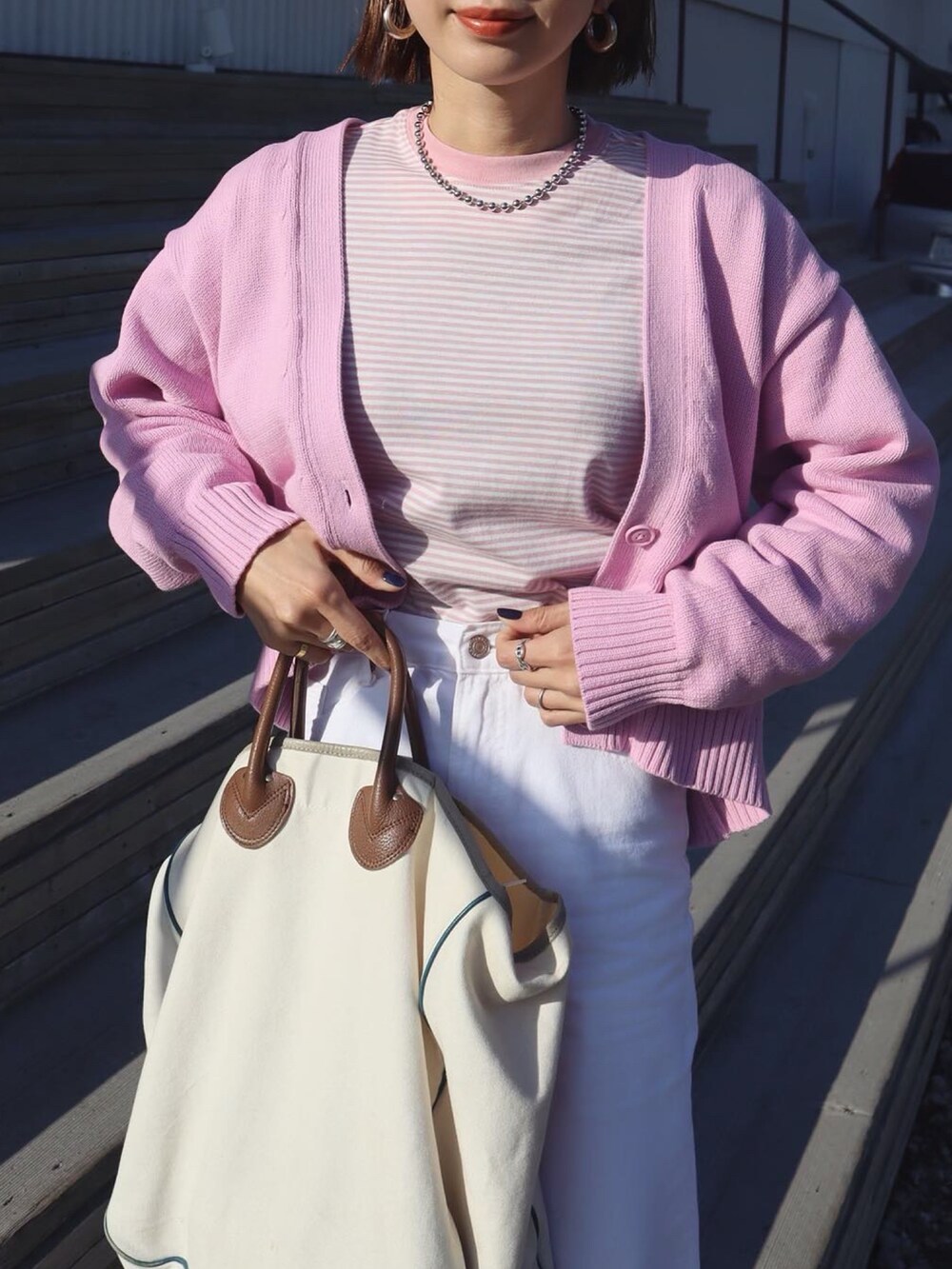 ピンク系のTシャツ/カットソー、ピンク系のカーディガン/ボレロ、ホワイト系のデニムパンツを着用したレディースの冬コーディネートの2枚目の写真