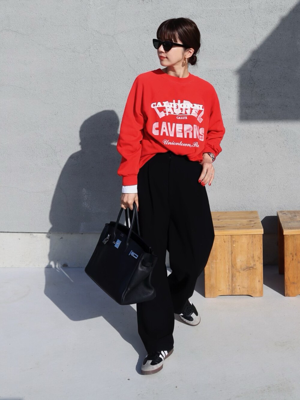 レッド系のスウェット、ブラック系のスラックス、ブラック系のスニーカーを着用したレディースの春コーディネートの2枚目の写真