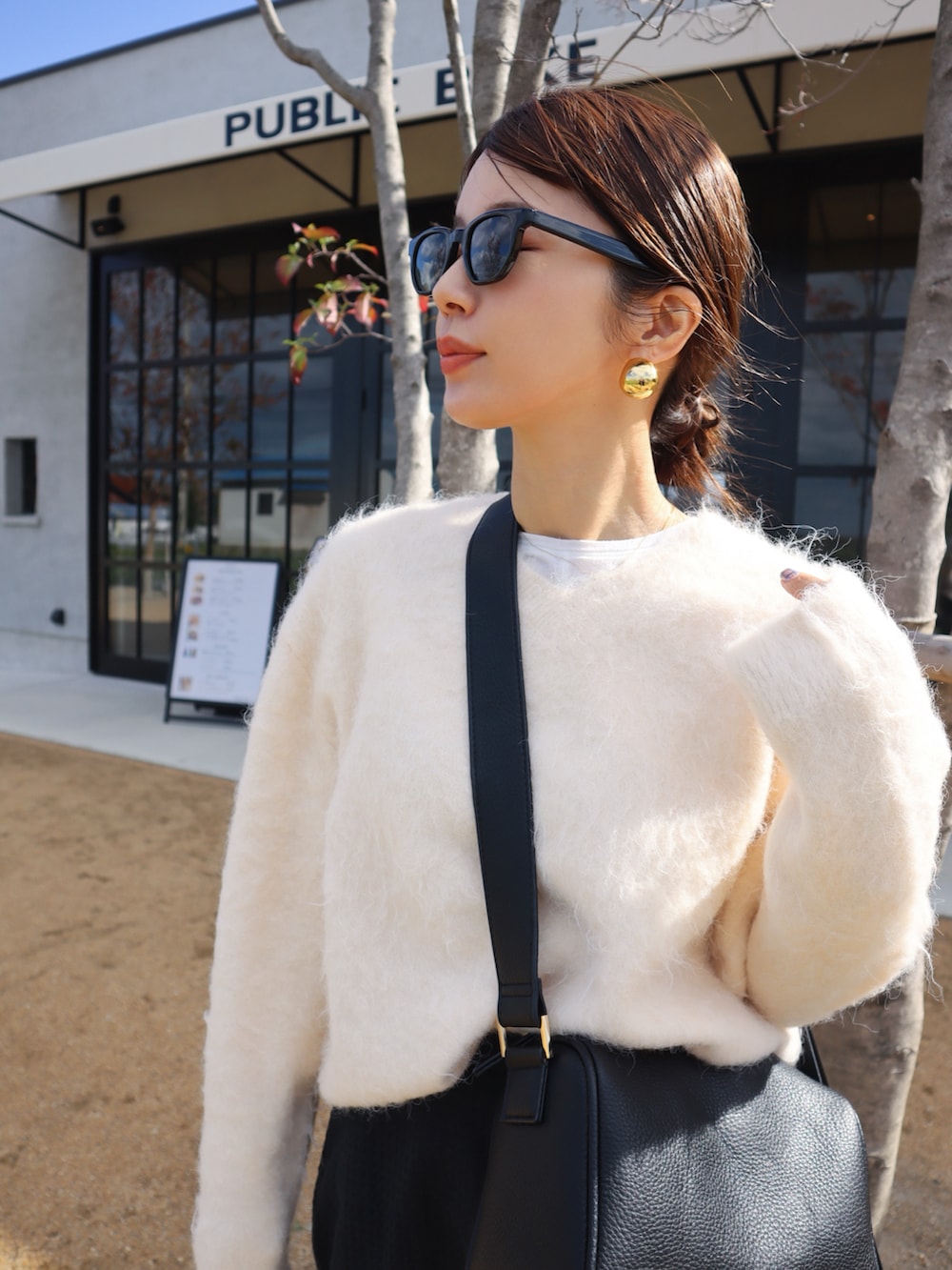 イエロー系のテーラードジャケット、ホワイト系のニット/セーター、ブラック系のスカートを着用したレディースの秋コーディネートの3枚目の写真