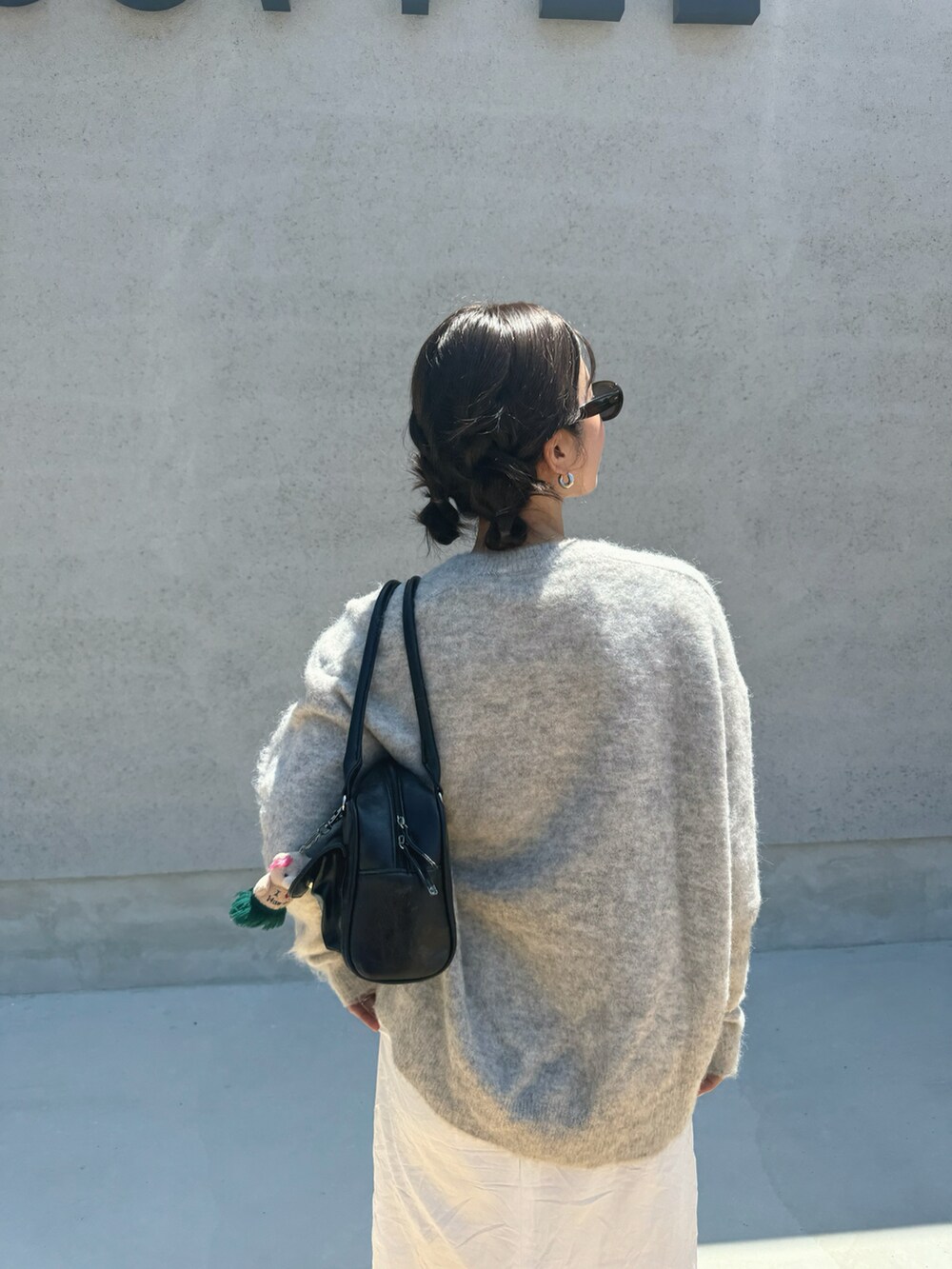 グレー系のニット/セーター、ホワイト系のスカート、ブラック系のボストンバッグを着用したレディースの夏コーディネートの3枚目の写真