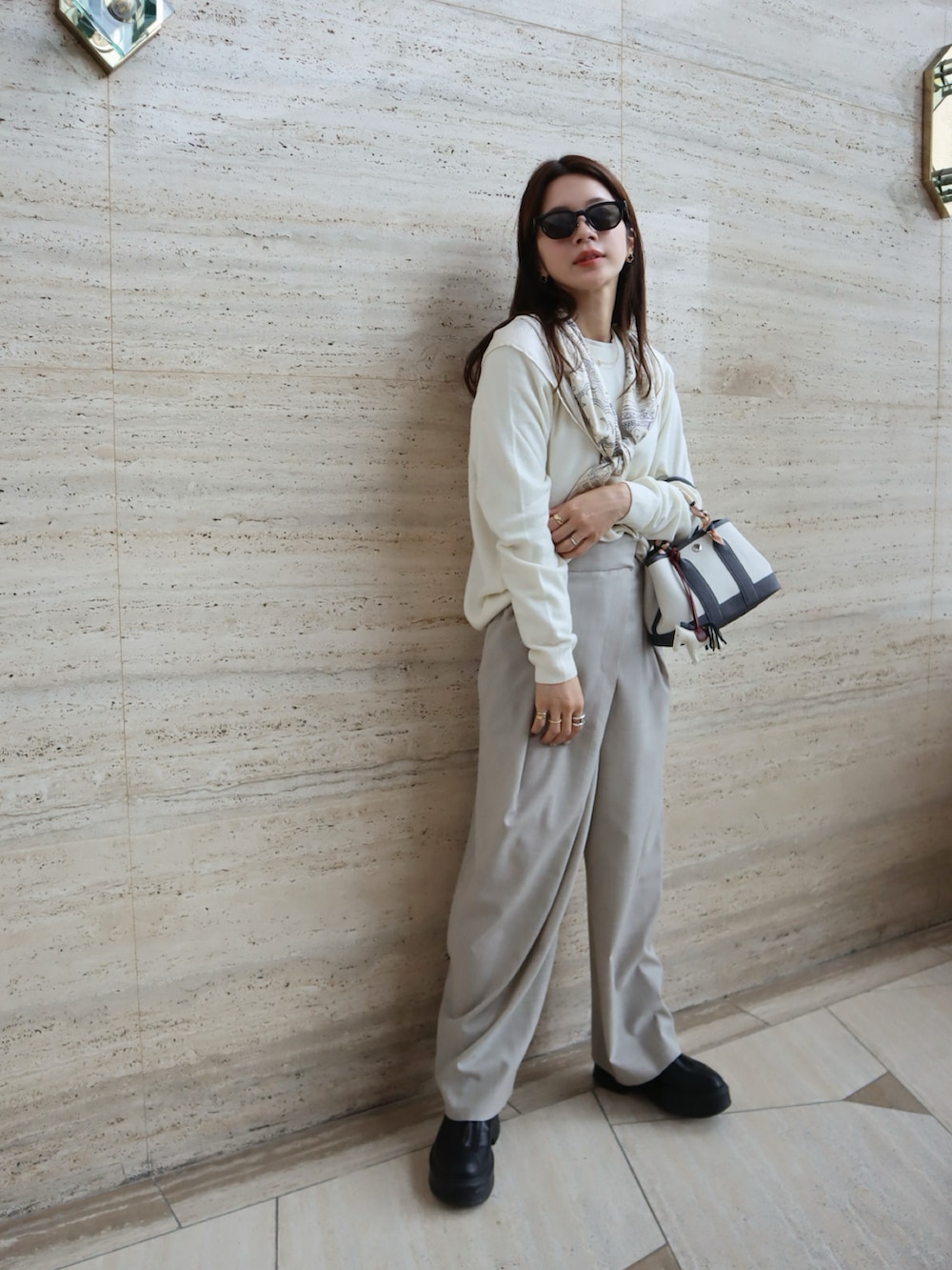 ブラック系のブーツ、ホワイト系のニット/セーター、グレー系のスラックスを着用したレディースの秋コーディネートの2枚目の写真