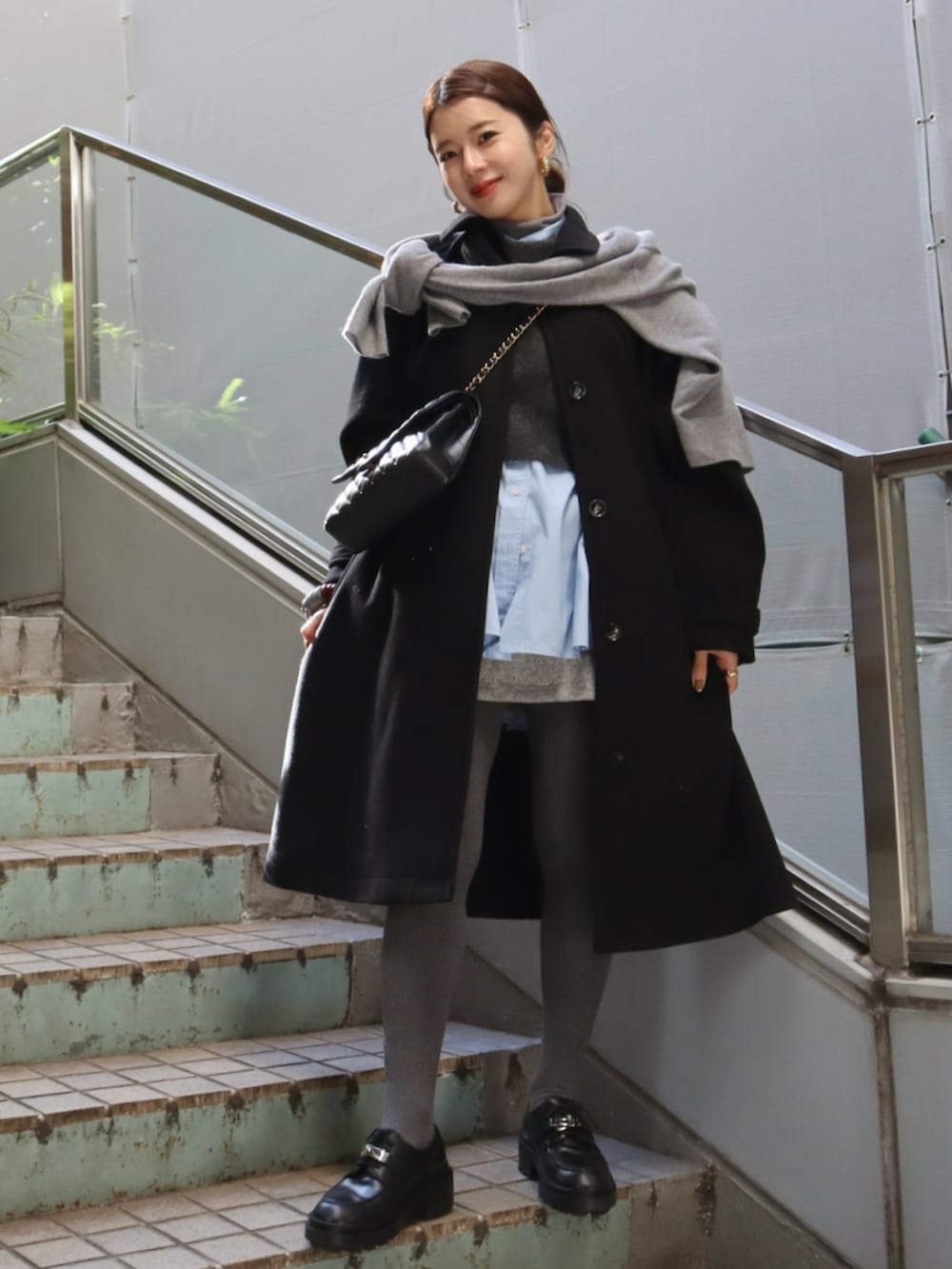 ブラック系のその他アウター、ブラック系のローファー、ブルー系のシャツ/ブラウスを着用したレディースの冬コーディネートの2枚目の写真