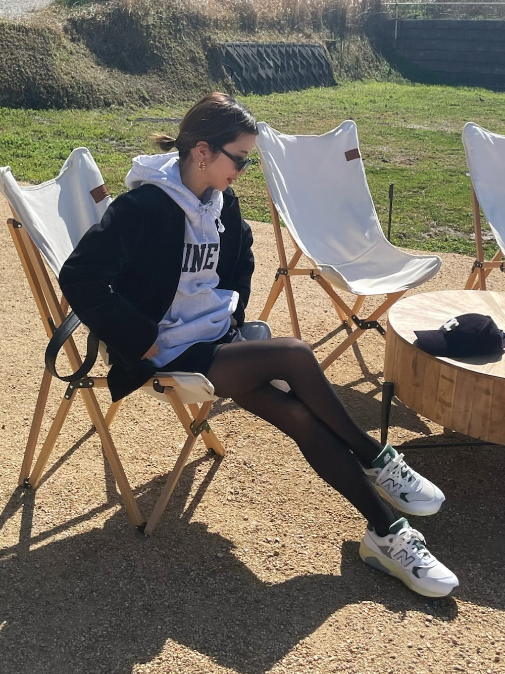 ホワイト系のスニーカー、ブルー系のパンツ、ブラック系のショルダーバッグを着用したレディースの春コーディネートの2枚目の写真