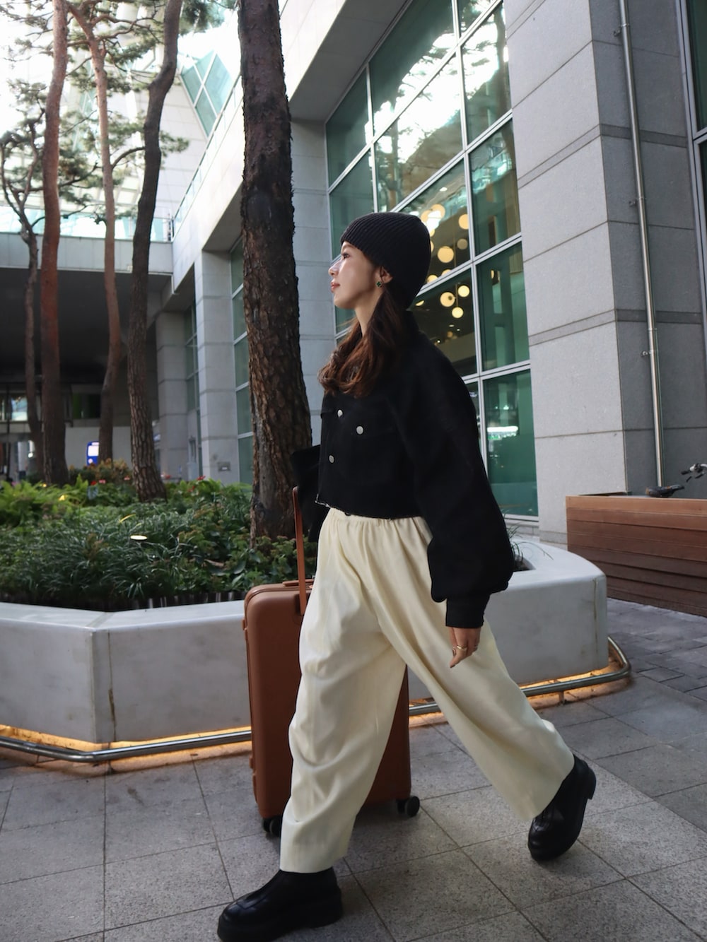 ホワイト系のその他パンツ、ブラック系のデニムジャケット、ブラウン系のスーツケース/キャリーバッグを着用したレディースの秋コーディネートの2枚目の写真