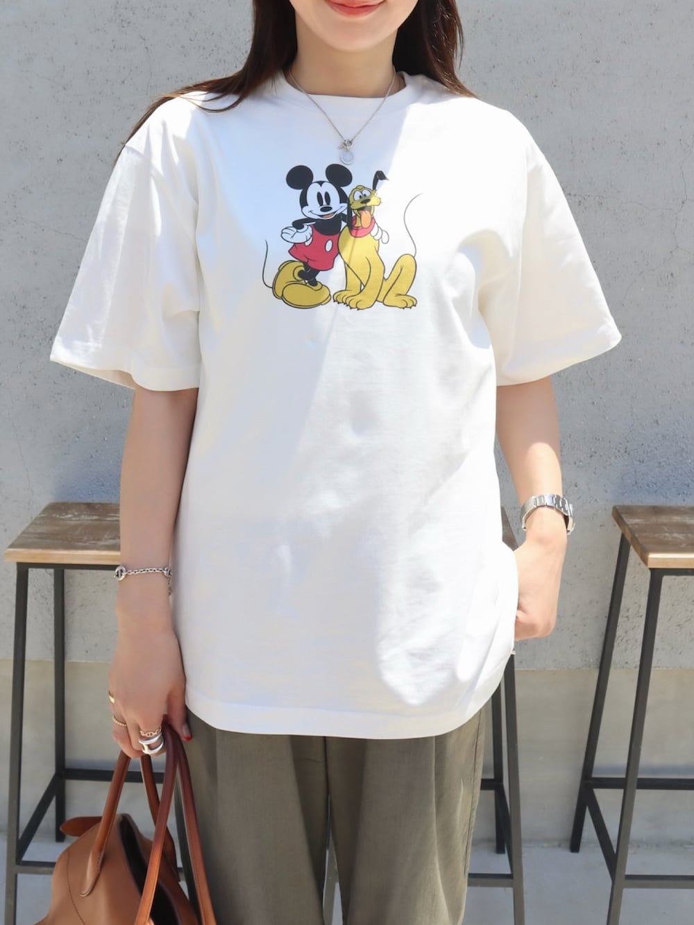 ホワイト系のTシャツ/カットソー、ブラウン系のハンドバッグ、シルバー系のスニーカーを着用したレディースの夏コーディネートの2枚目の写真