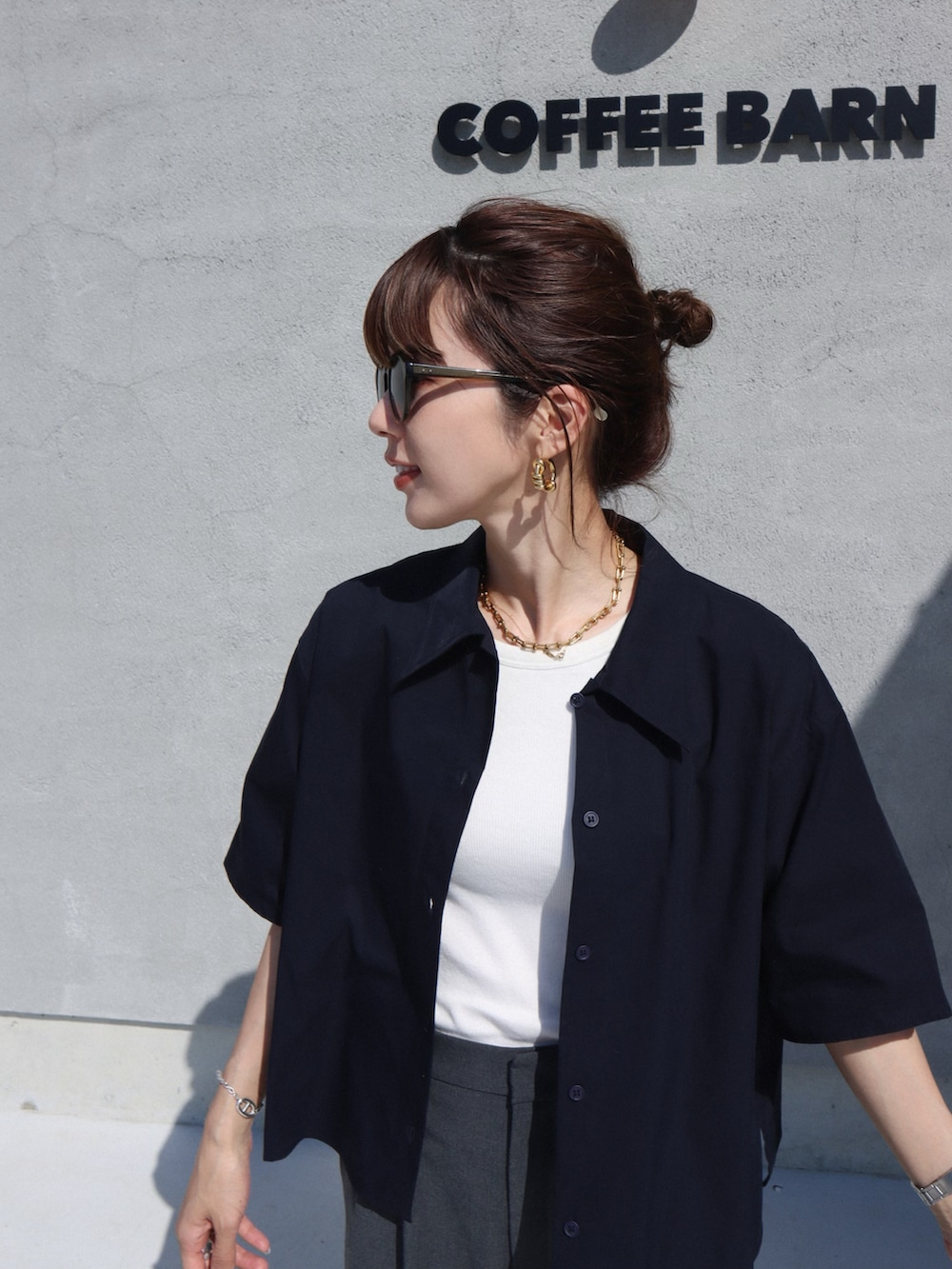 グレー系のスラックス、ブラック系のスニーカー、ホワイト系のアンダーウェアを着用したレディースの春コーディネートの2枚目の写真