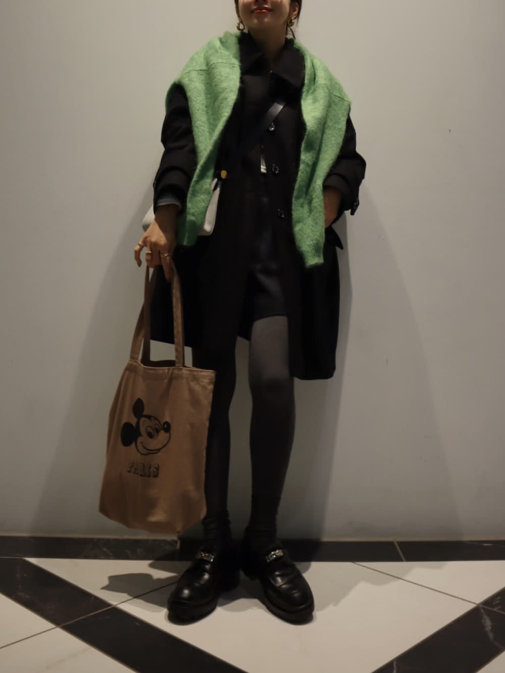 ブラック系のステンカラーコート、ブラウン系のトートバッグ、ブラック系のローファーを着用したレディースの冬コーディネートの3枚目の写真