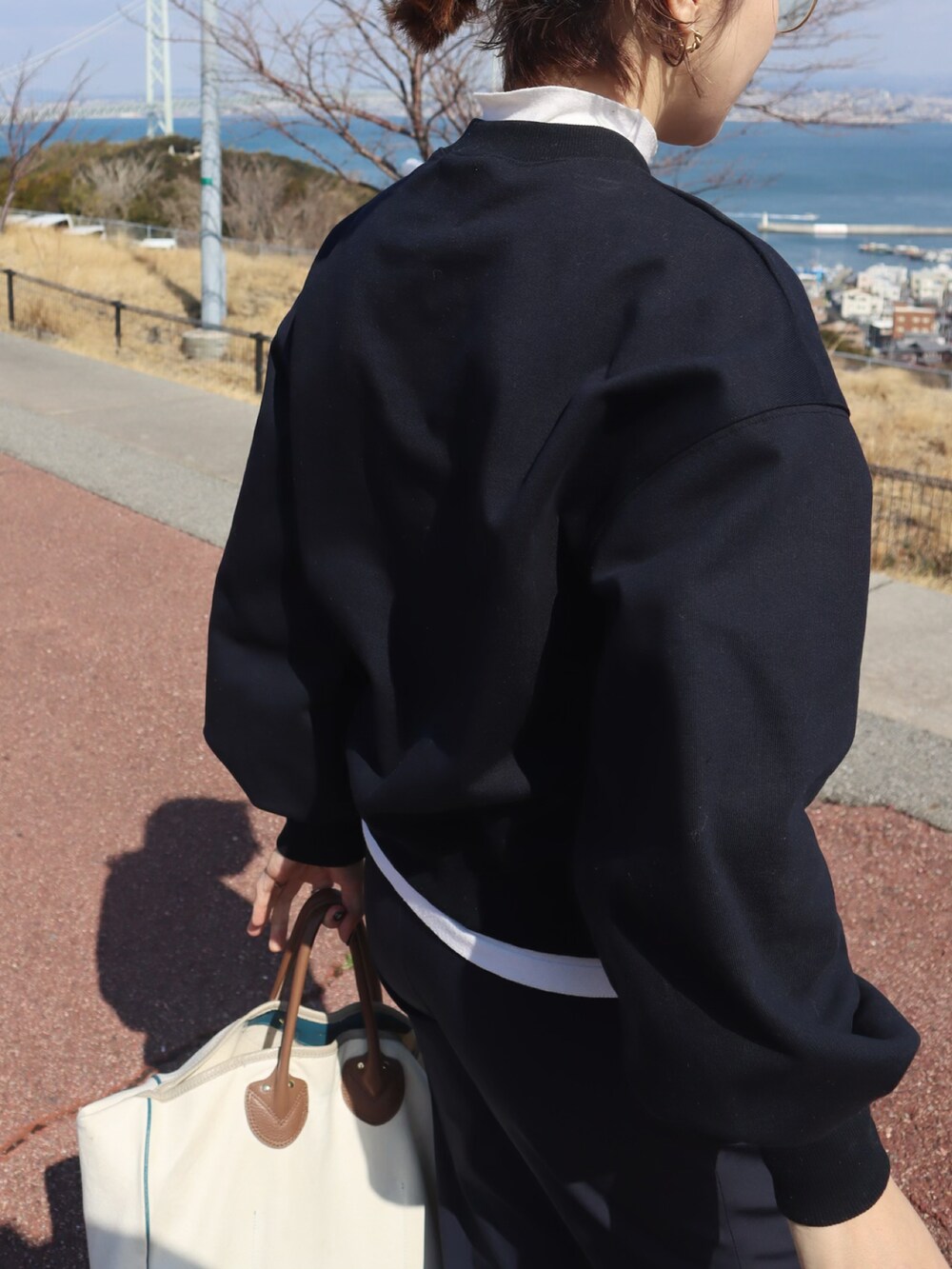 ブラック系のブルゾン、ホワイト系のTシャツ/カットソー、ブルー系のスウェットを着用したレディースの冬コーディネートの2枚目の写真