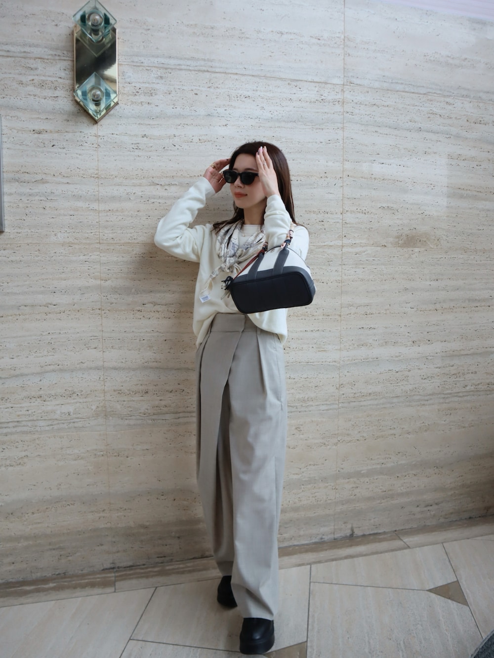 ブラック系のブーツ、ホワイト系のニット/セーター、グレー系のスラックスを着用したレディースの秋コーディネートの3枚目の写真