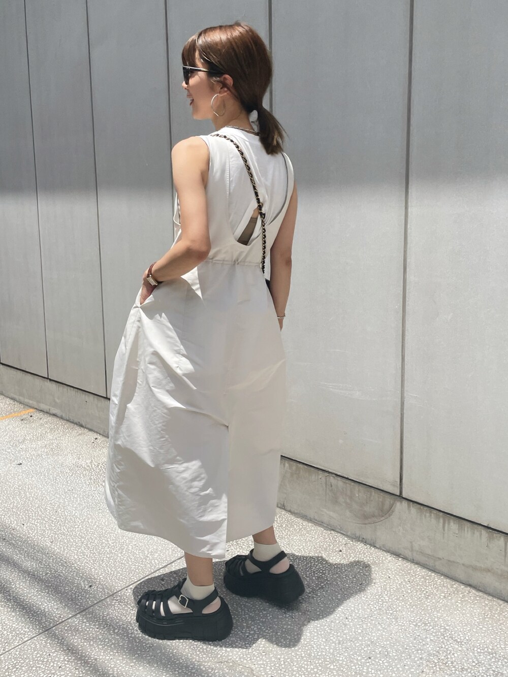 ホワイト系のタンクトップ、ホワイト系のジャンパースカート、ブラック系のサンダルを着用したレディースの夏コーディネートの2枚目の写真