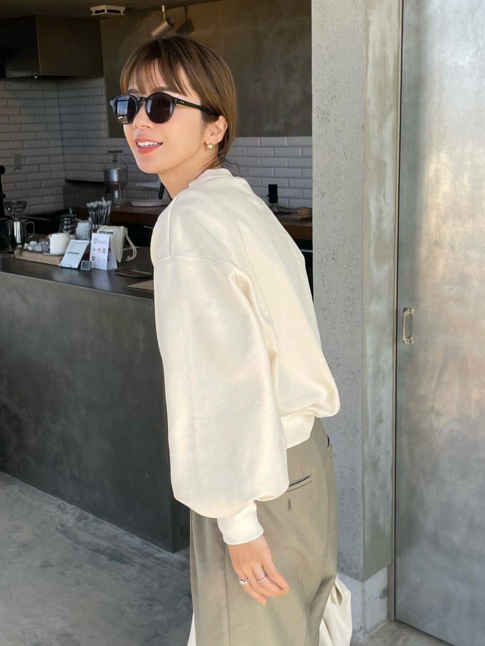 ホワイト系のスウェット、グリーン系のスラックス、ブラック系のベルトを着用したレディースの冬コーディネートの2枚目の写真