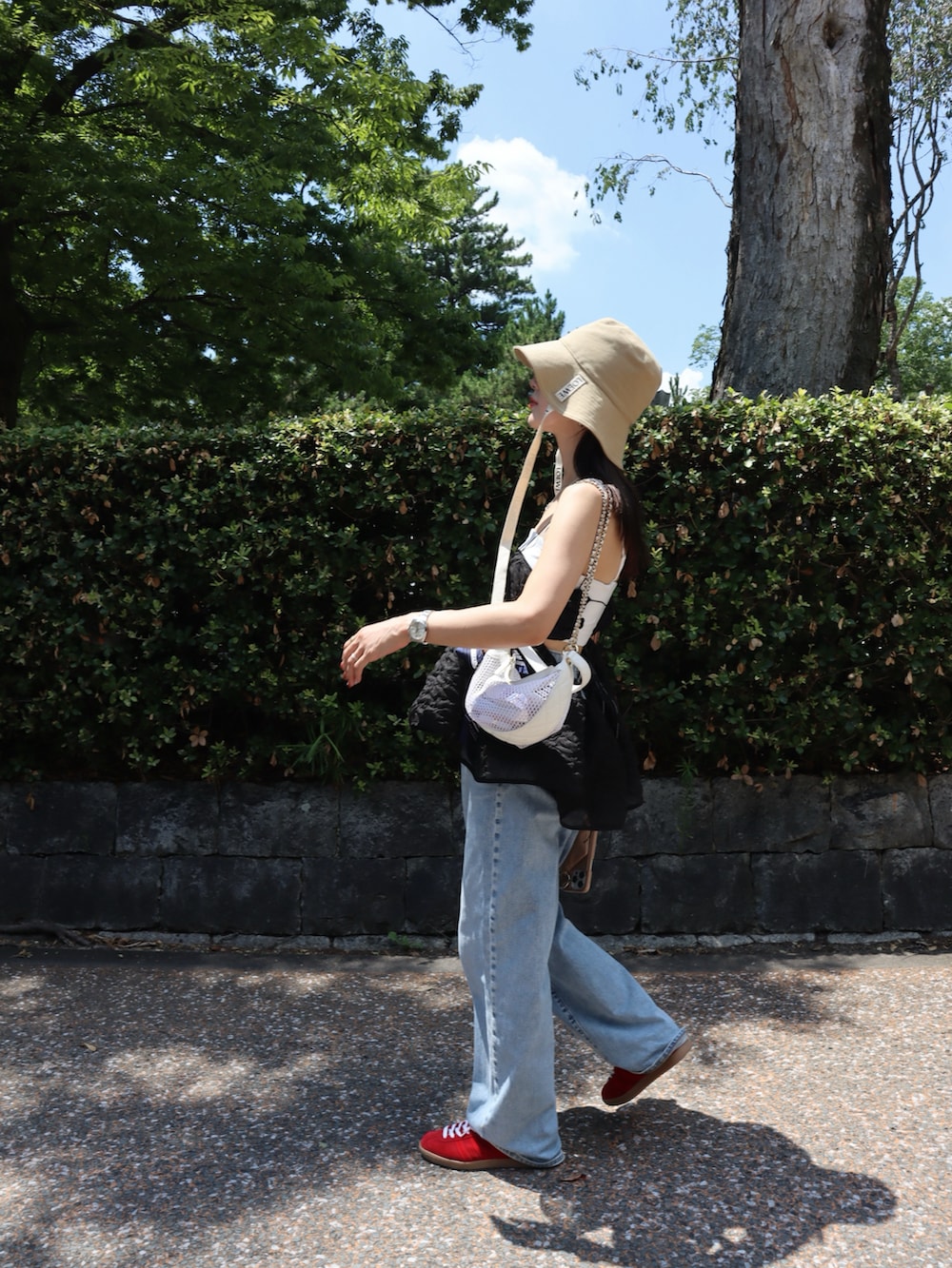 ブルー系のデニムパンツ、ブラック系のその他トップス、レッド系のスニーカーを着用したレディースの夏コーディネートの3枚目の写真