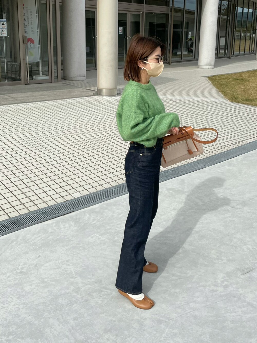 グリーン系のニット/セーター、ブルー系のデニムパンツ、ブラウン系のバレエシューズを着用したレディースの秋コーディネートの3枚目の写真