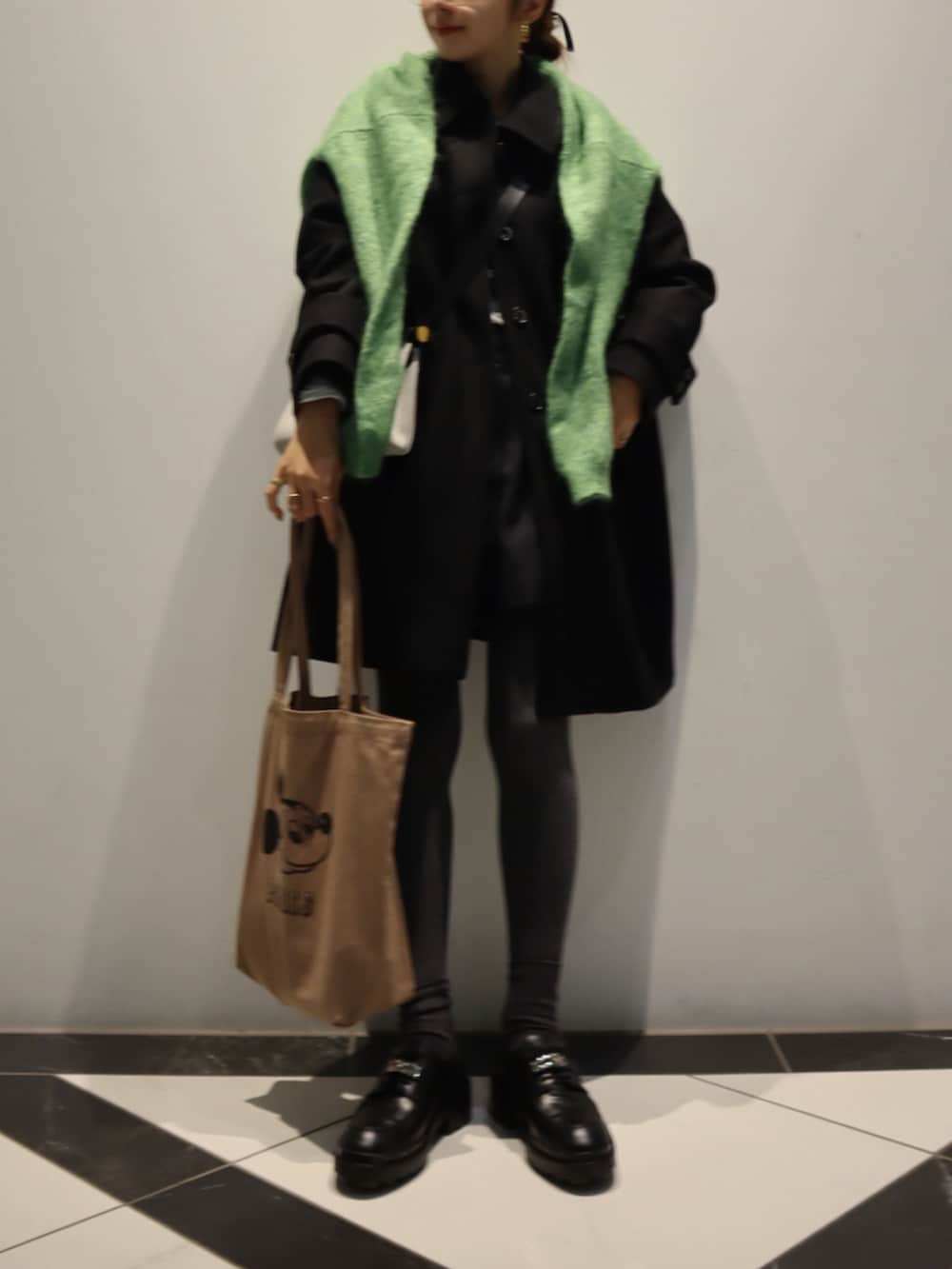 ブラック系のステンカラーコート、ブラウン系のトートバッグ、ブラック系のローファーを着用したレディースの冬コーディネートの2枚目の写真