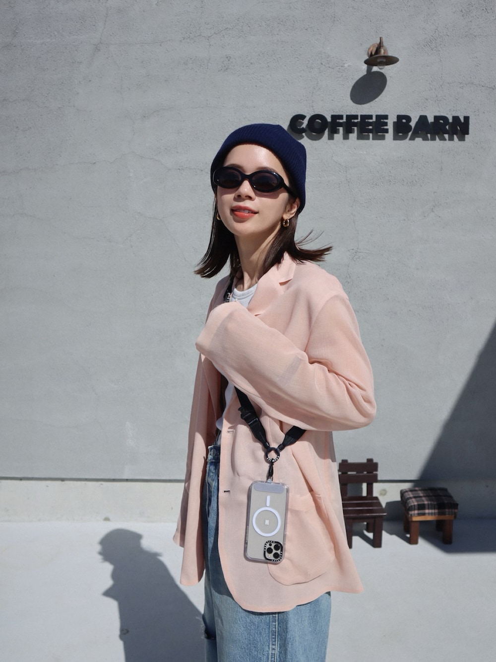 ピンク系のテーラードジャケット、ブラウン系のショルダーバッグ、ゴールド系のピアス（両耳用）を着用したレディースの春コーディネートの2枚目の写真