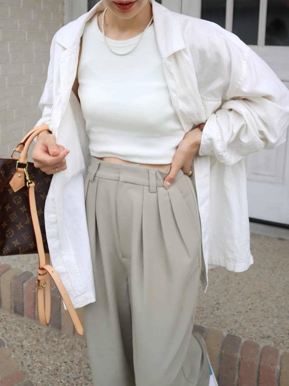 ホワイト系のタンクトップ、ベージュ系のスラックス、ブルー系のキャップを着用したレディースの夏コーディネートの2枚目の写真