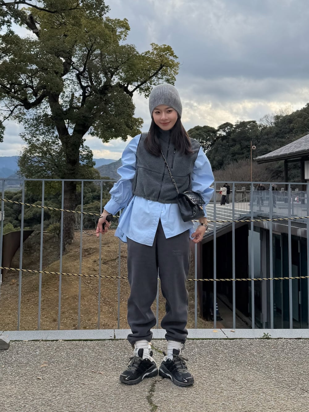 ブラック系のその他パンツ、ブラック系のスニーカー、グレー系のベストを着用したレディースの冬コーディネートの2枚目の写真