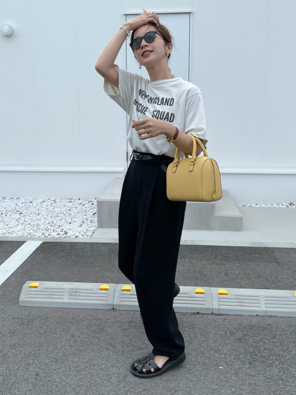 ベージュ系のTシャツ/カットソー、ブラック系のスラックス、イエロー系のボストンバッグを着用したレディースの夏コーディネートの2枚目の写真