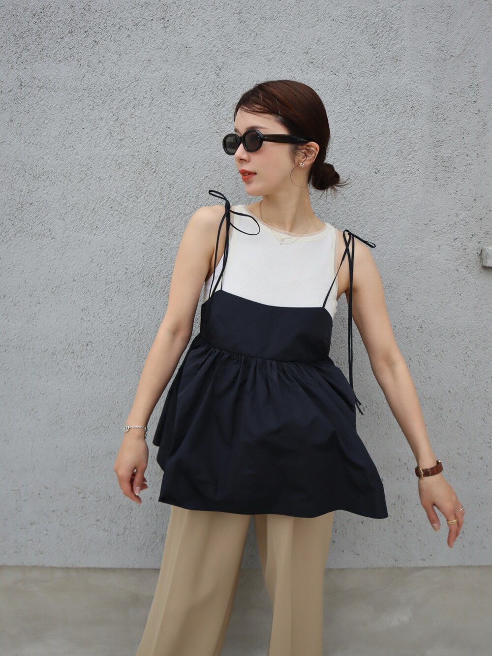 ブラウン系のスニーカー、ブラック系のキャミソール、ベージュ系のスラックスを着用したレディースの春コーディネートの3枚目の写真