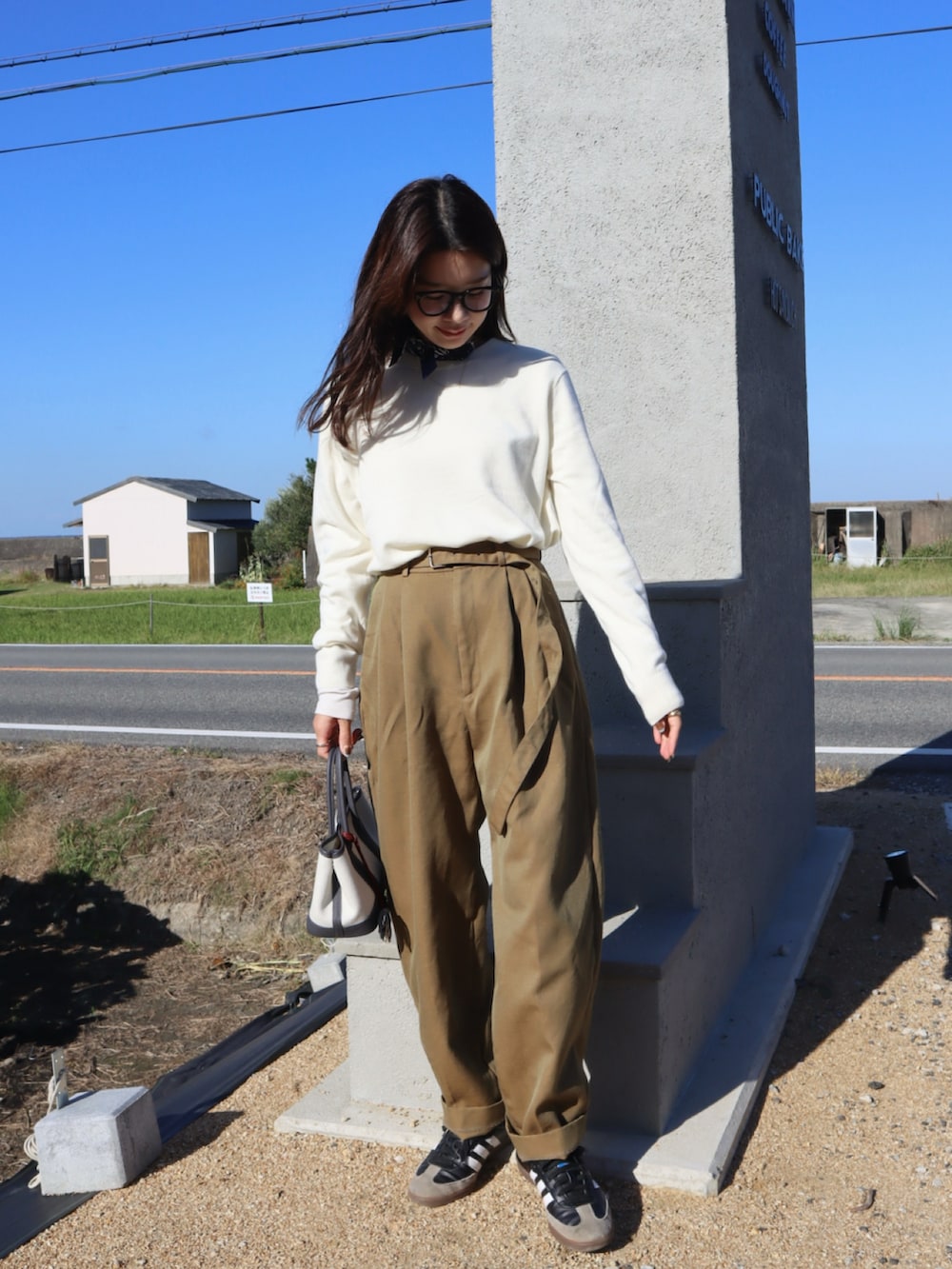 ベージュ系のその他パンツ、ホワイト系のニット/セーター、ブラック系のスニーカーを着用したレディースの秋コーディネートの2枚目の写真