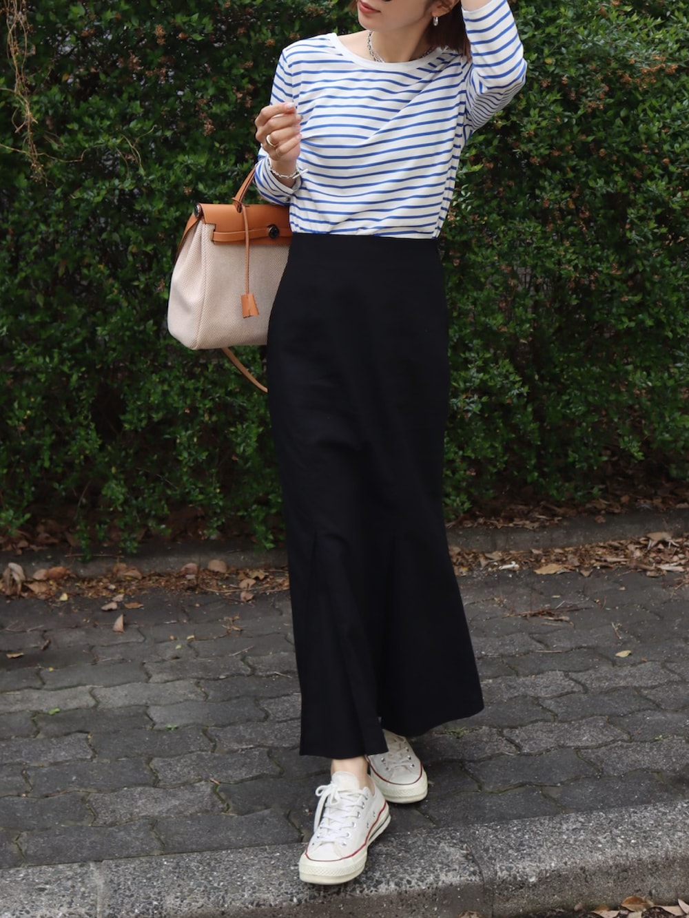 ブラック系のスカート、ホワイト系のデニムジャケット、ホワイト系のスニーカーを着用したレディースの春コーディネートの2枚目の写真