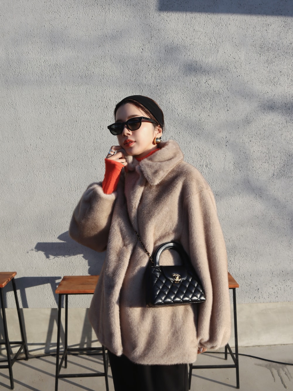 ベージュ系のステンカラーコート、ブラック系のスラックス、ブラック系のブーツを着用したレディースの冬コーディネートの2枚目の写真