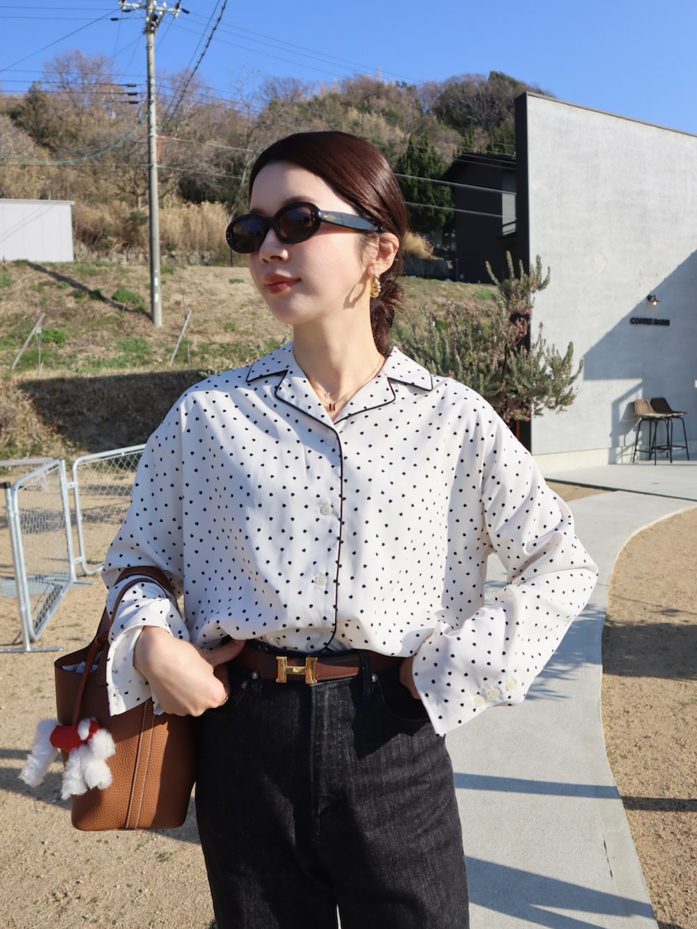 ホワイト系のシャツ/ブラウス、ブラック系のデニムパンツ、ブラウン系のハンドバッグを着用したレディースの春コーディネートの3枚目の写真