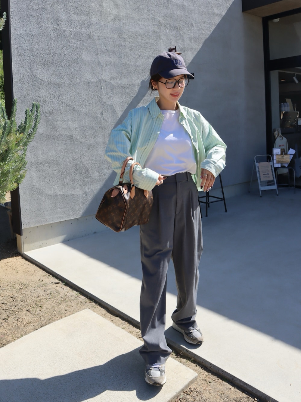 グリーン系のシャツ/ブラウス、グレー系のスラックス、ブラウン系のハンドバッグを着用したレディースの秋コーディネートの2枚目の写真