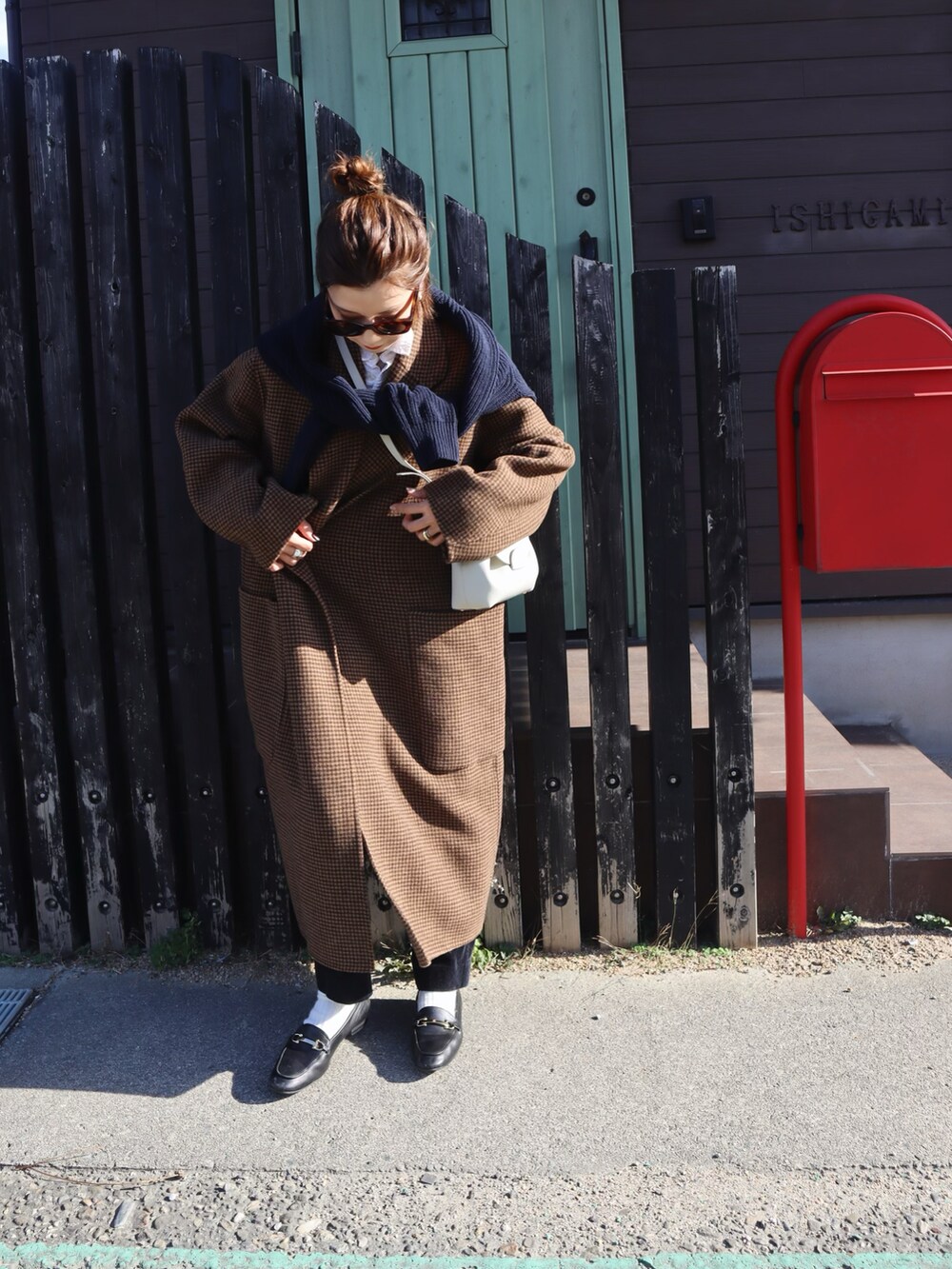 ブルー系のニット/セーター、ブラウン系のチェスターコート、ブラック系のローファーを着用したレディースの冬コーディネートの2枚目の写真