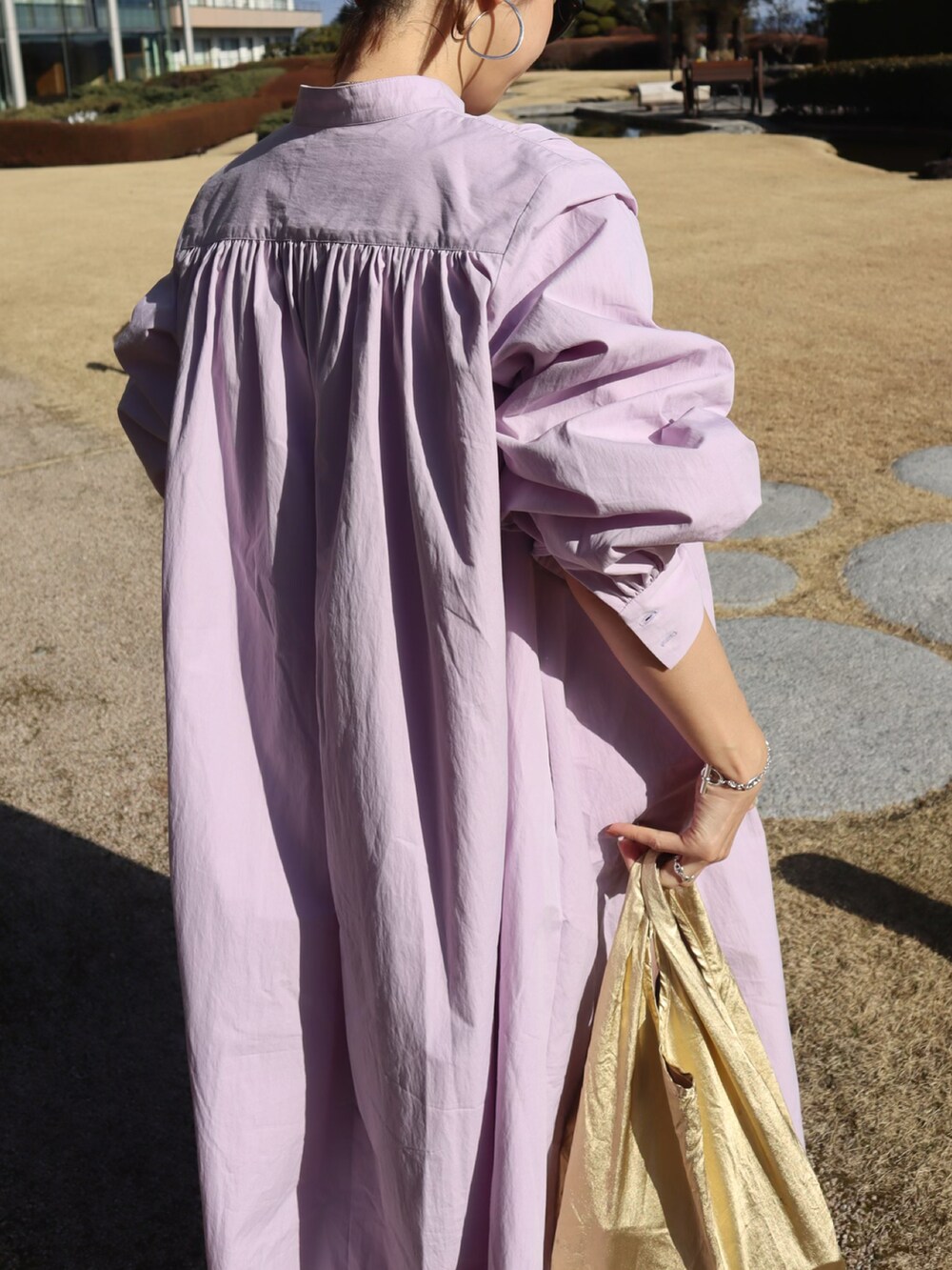 パープル系のシャツワンピース、ゴールド系のエコバッグ/サブバッグ、ベージュ系のサンダルを着用したレディースの冬コーディネートの3枚目の写真