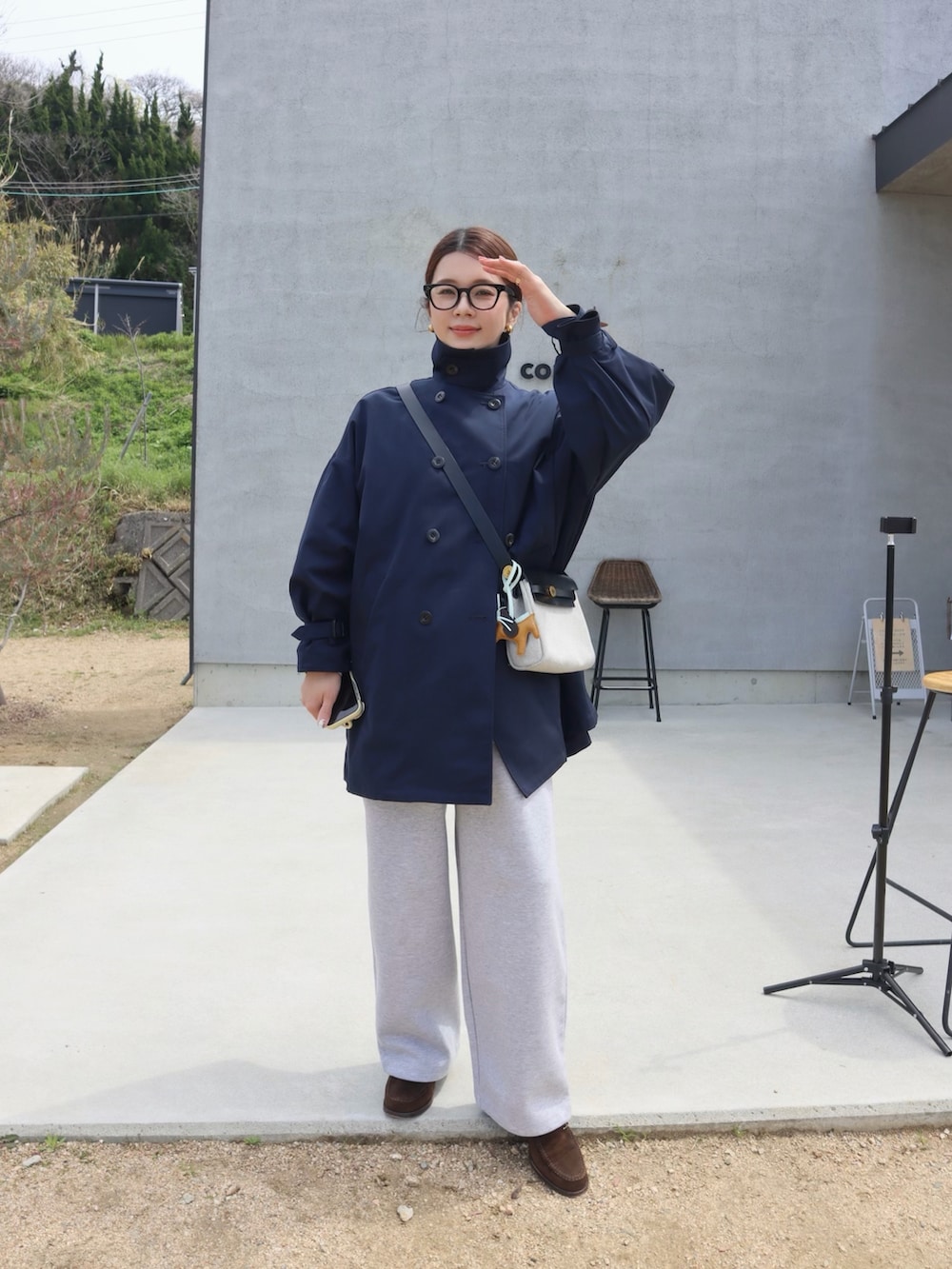 ブルー系のトレンチコート、グレー系のスウェットパンツ、ブラウン系のローファーを着用したレディースの春コーディネートの2枚目の写真