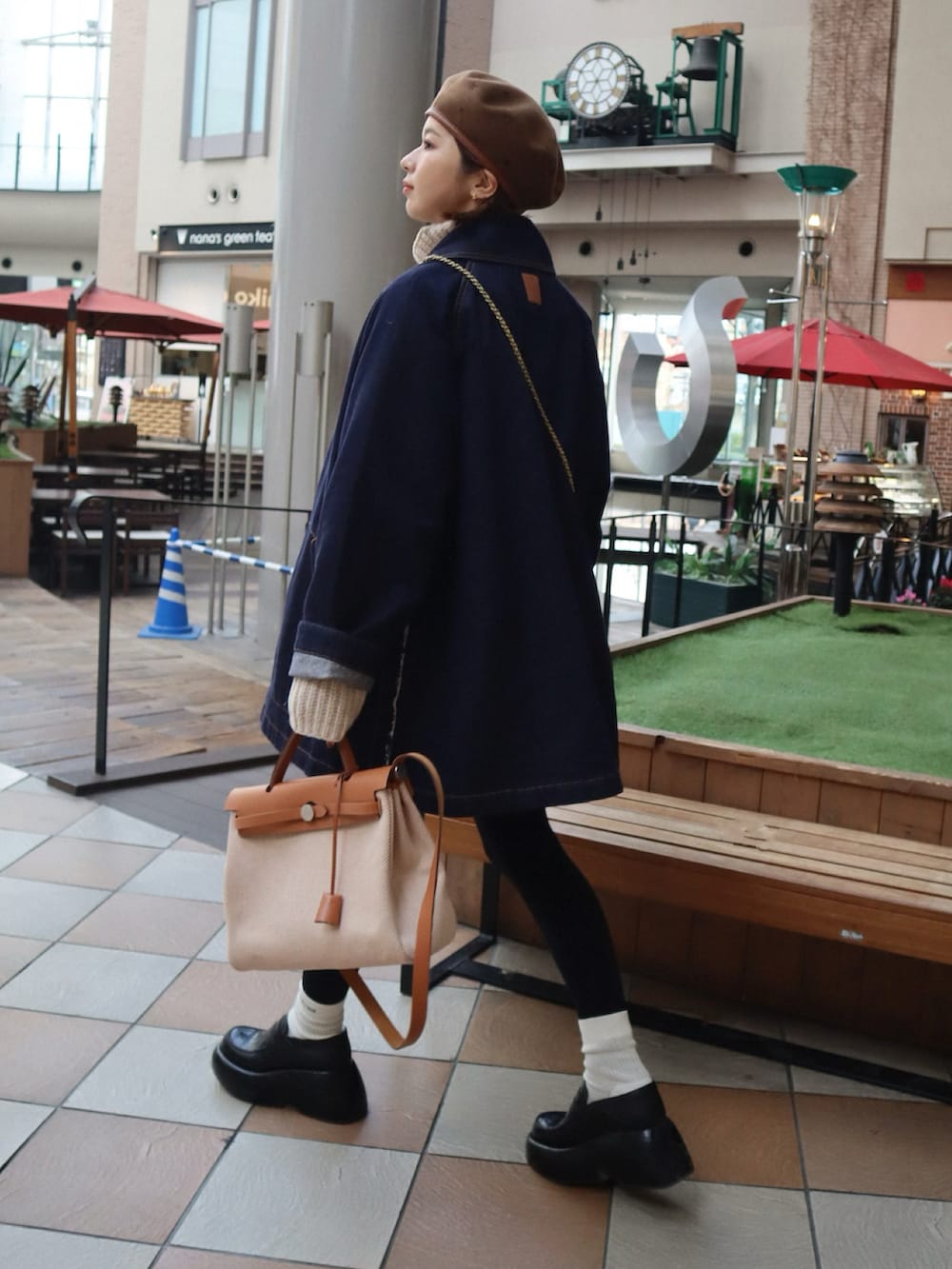 ブラック系のローファー、ベージュ系のハンドバッグ、ブルー系のデニムジャケットを着用したレディースの冬コーディネートの2枚目の写真