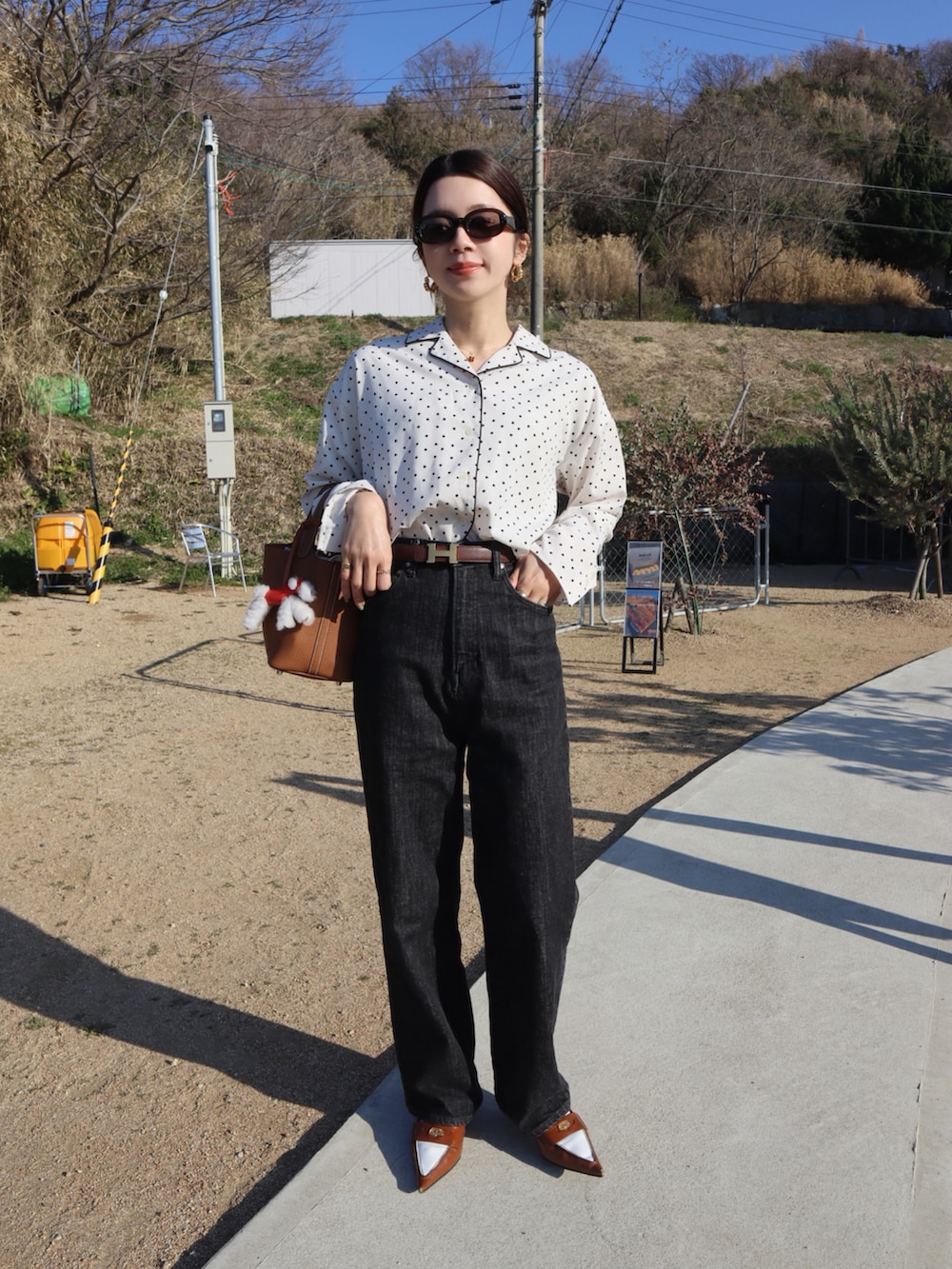 ホワイト系のシャツ/ブラウス、ブラック系のデニムパンツ、ブラウン系のハンドバッグを着用したレディースの春コーディネートの2枚目の写真