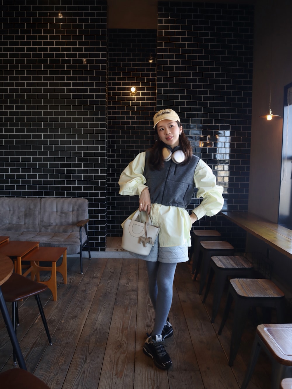 グレー系のベスト、イエロー系のシャツ/ブラウス、ブラック系のスニーカーを着用したレディースの冬コーディネートの2枚目の写真