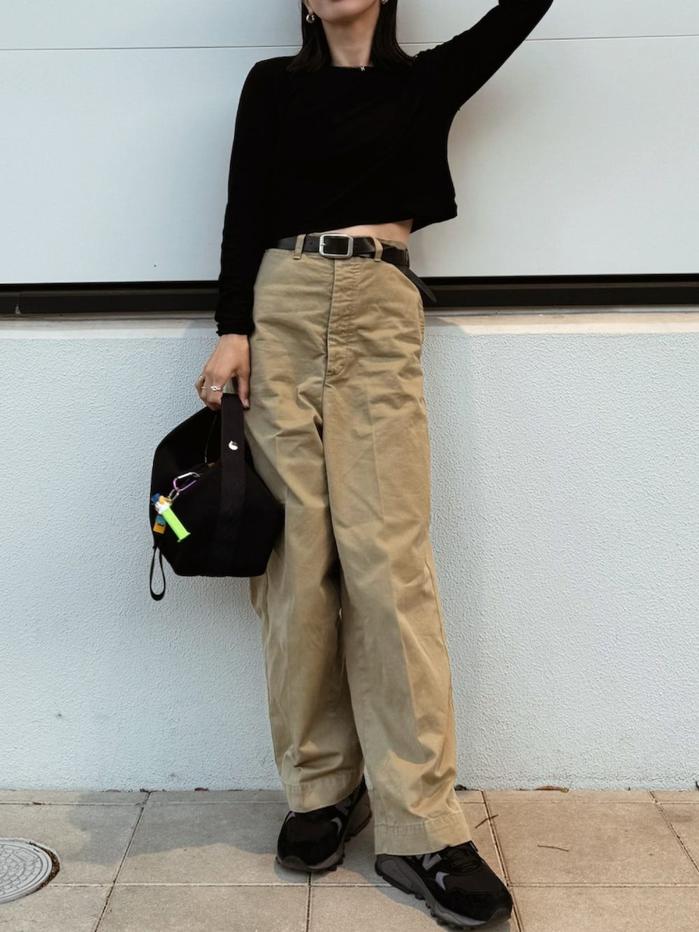 ブラック系のTシャツ/カットソー、ベージュ系のチノパンツ、ブラック系のスニーカーを着用したレディースの春コーディネートの2枚目の写真