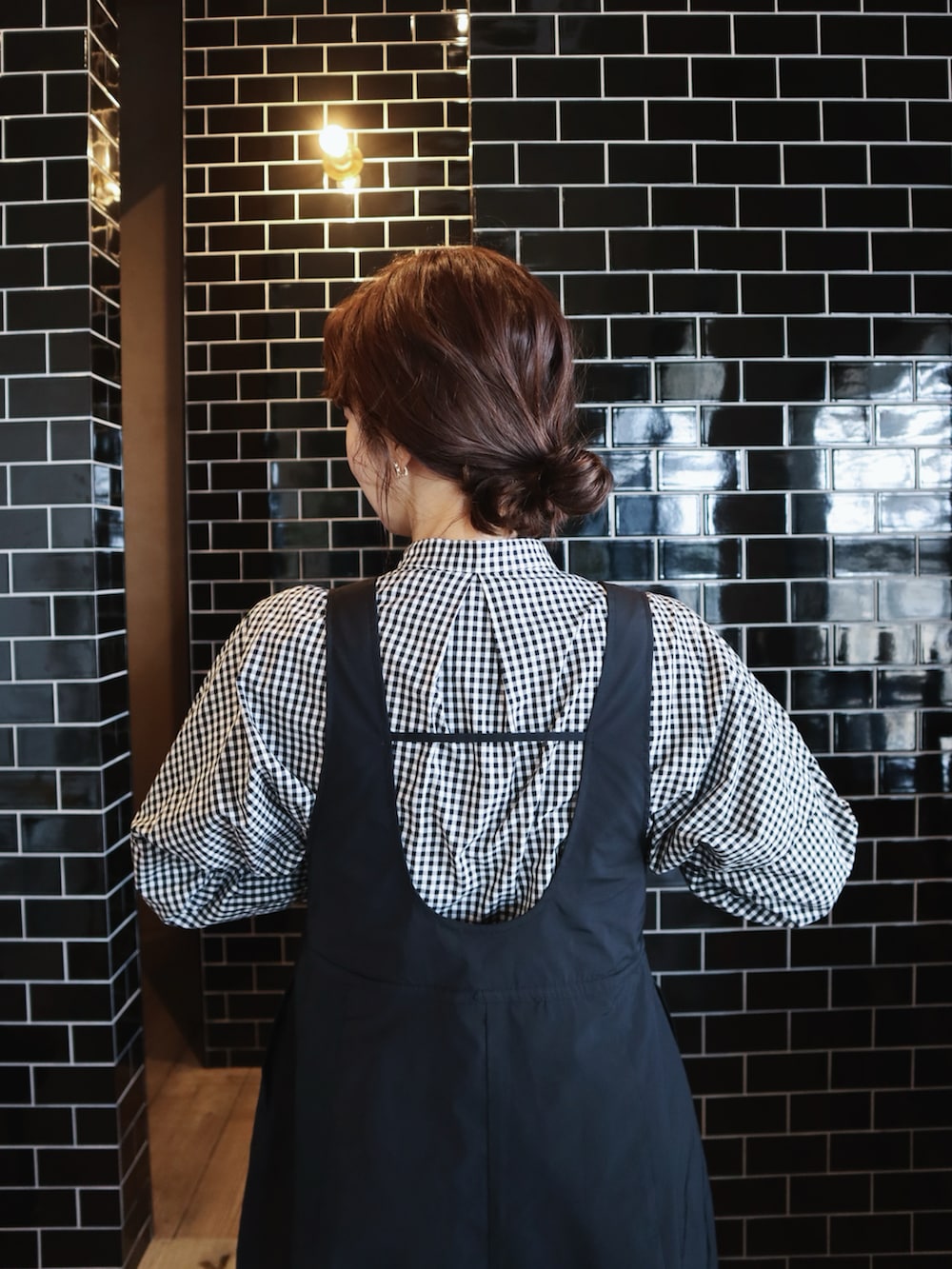 ブラック系のシャツ/ブラウス、ブラック系のジャンパースカート、ブラック系のスニーカーを着用したレディースの冬コーディネートの2枚目の写真
