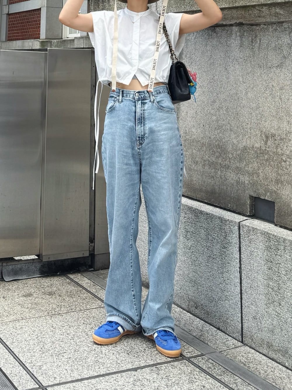 ブルー系のデニムパンツ、ブルー系のスニーカー、ブラック系のショルダーバッグを着用したレディースの夏コーディネートの2枚目の写真