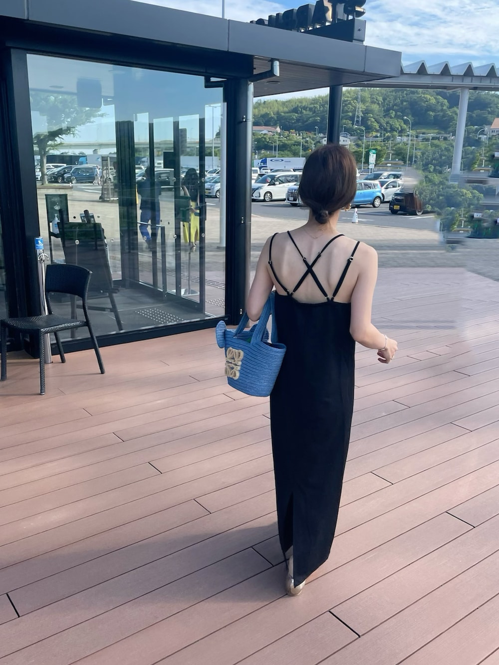 ブラック系のワンピース、ゴールド系のサンダル、ブルー系のトートバッグを着用したレディースの夏コーディネートの3枚目の写真