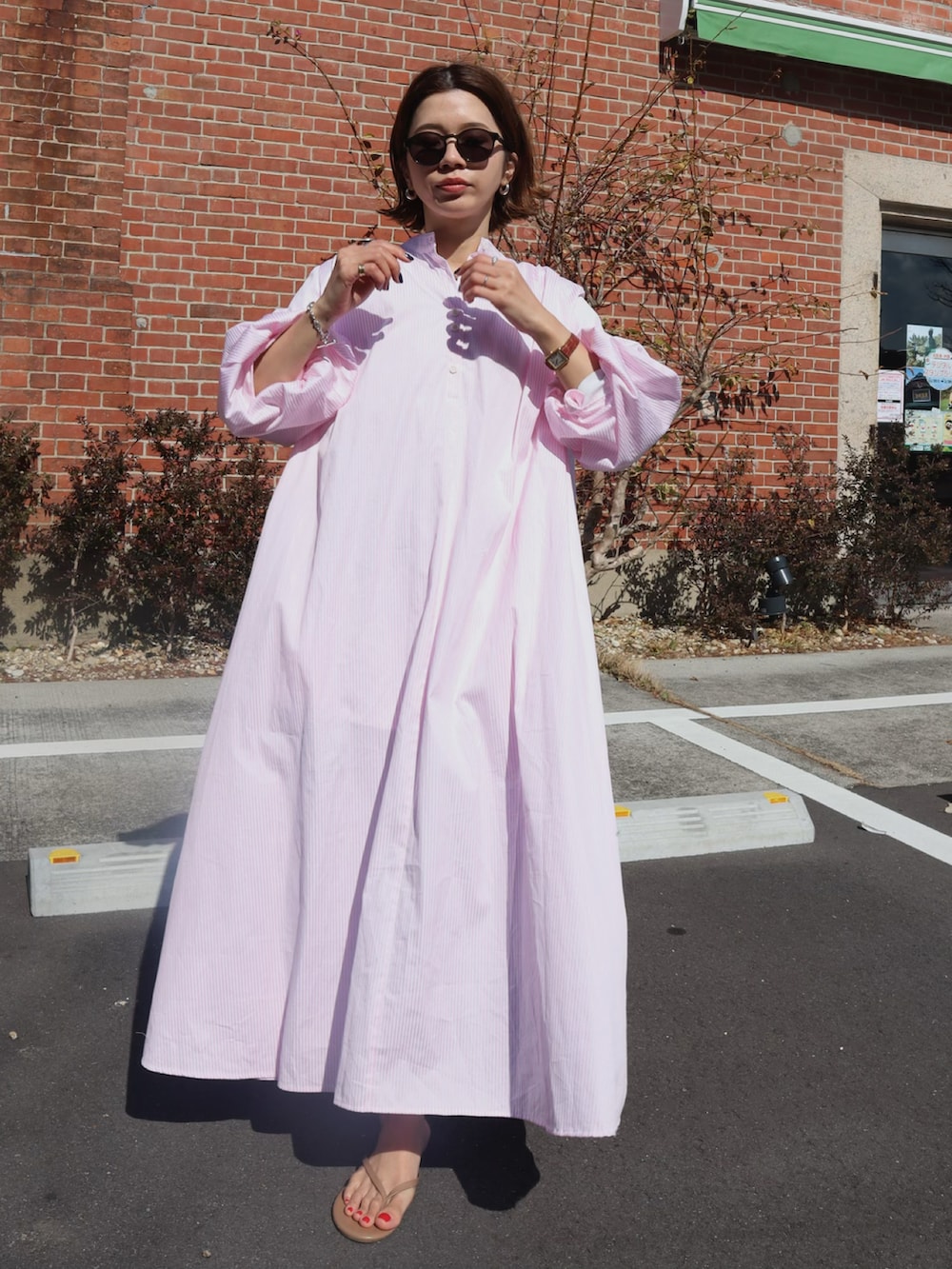 パープル系のシャツワンピース、ブラウン系のサンダル、グリーン系のサングラスを着用したレディースの冬コーディネートの2枚目の写真