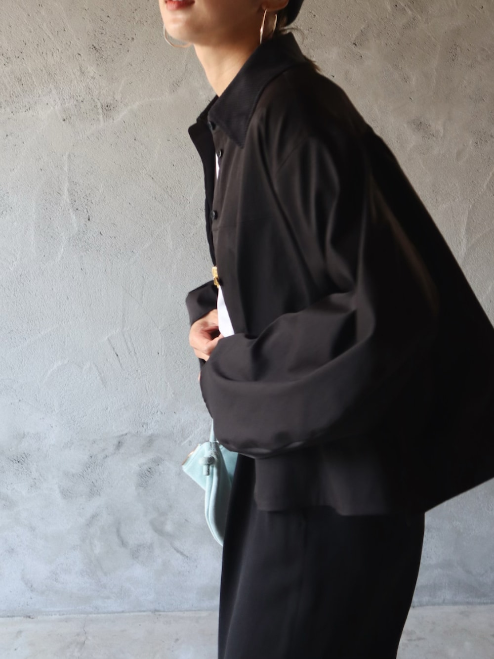 ブラック系のシャツ/ブラウス、ブラック系のスラックス、ホワイト系のスニーカーを着用したレディースの夏コーディネートの2枚目の写真