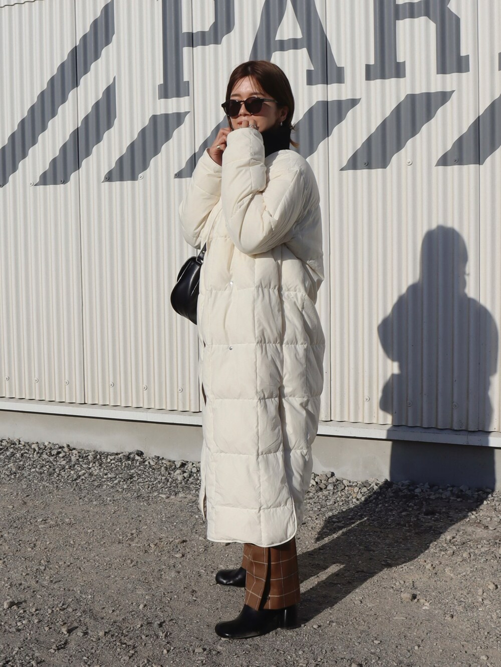 ホワイト系のダウンジャケット/コート、ブラウン系のパンツ、ブラック系のブーツを着用したレディースの冬コーディネートの2枚目の写真