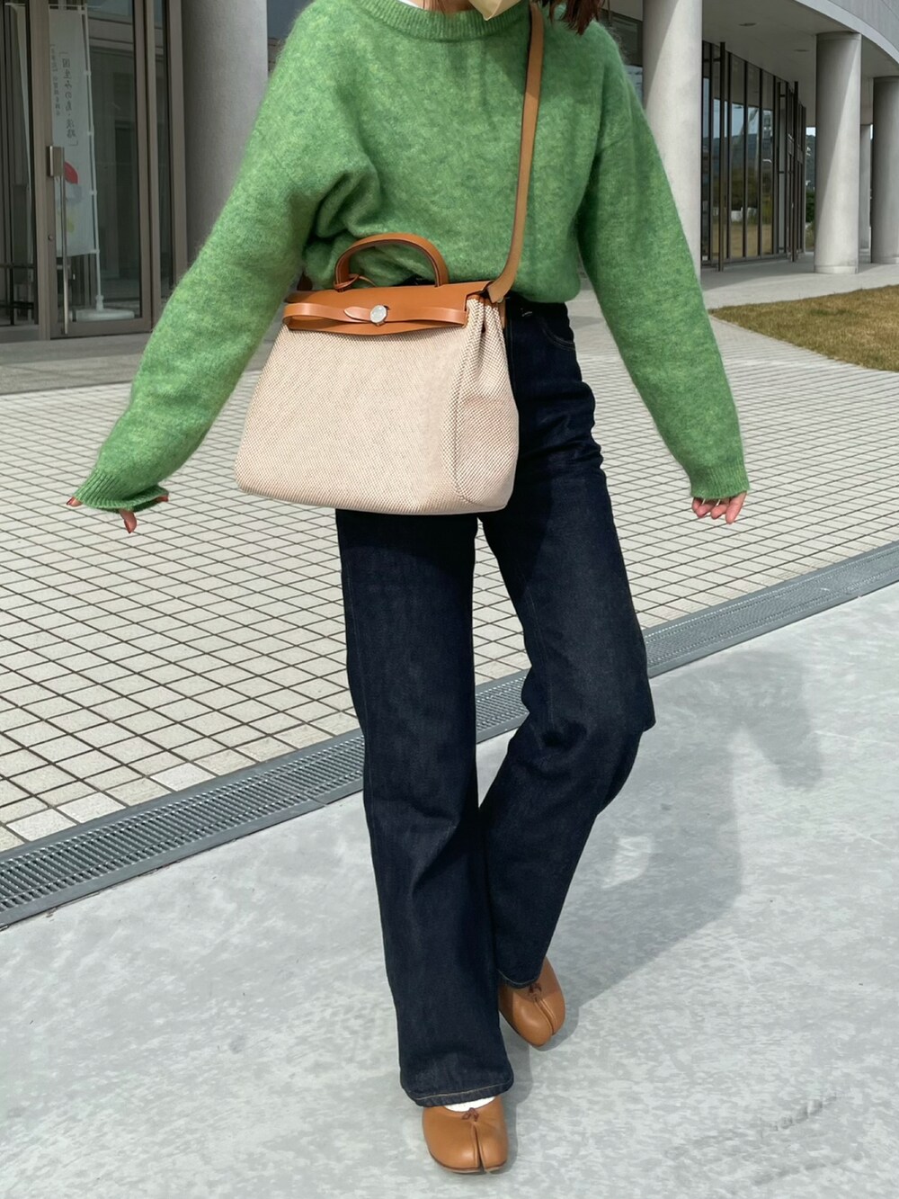 グリーン系のニット/セーター、ブルー系のデニムパンツ、ブラウン系のバレエシューズを着用したレディースの秋コーディネートの2枚目の写真