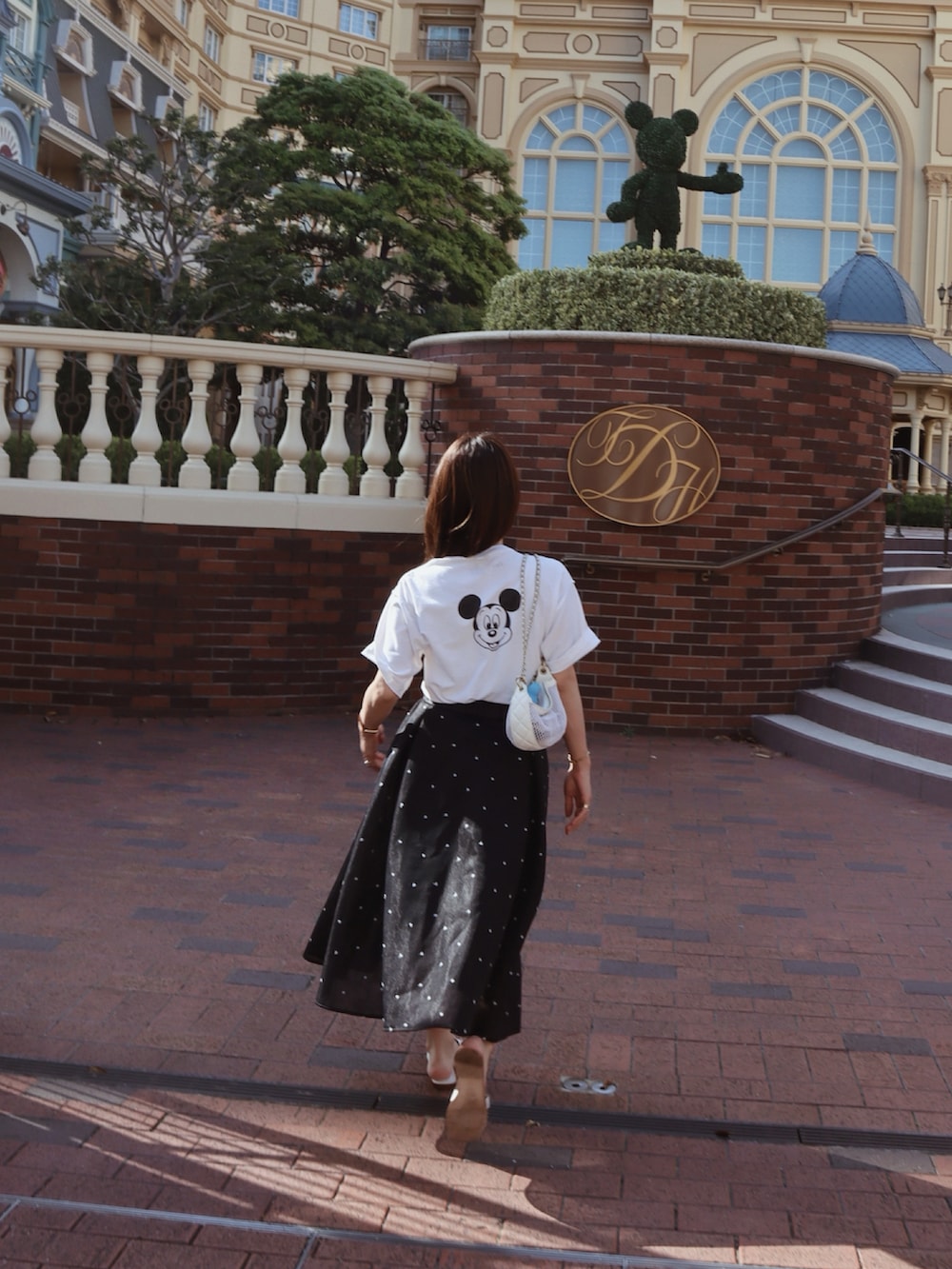 ホワイト系のTシャツ/カットソー、ブラック系のスカート、ホワイト系のサンダルを着用したレディースの夏コーディネートの2枚目の写真