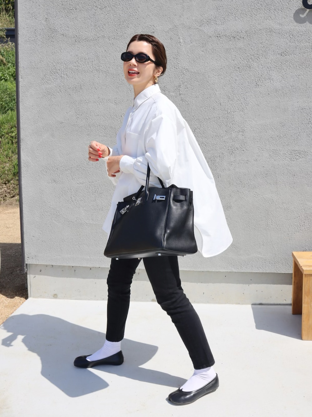 ブラック系のベスト、ホワイト系のシャツ/ブラウス、ブラック系のバレエシューズを着用したレディースの春コーディネートの2枚目の写真