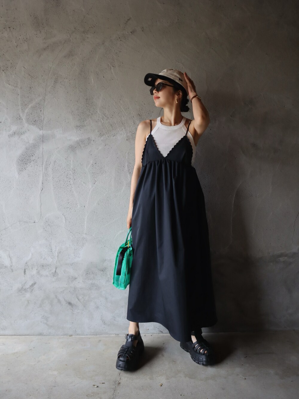 グリーン系のトートバッグ、ブラック系のワンピース/ドレス、ブラック系のサンダルを着用したレディースの春コーディネートの2枚目の写真