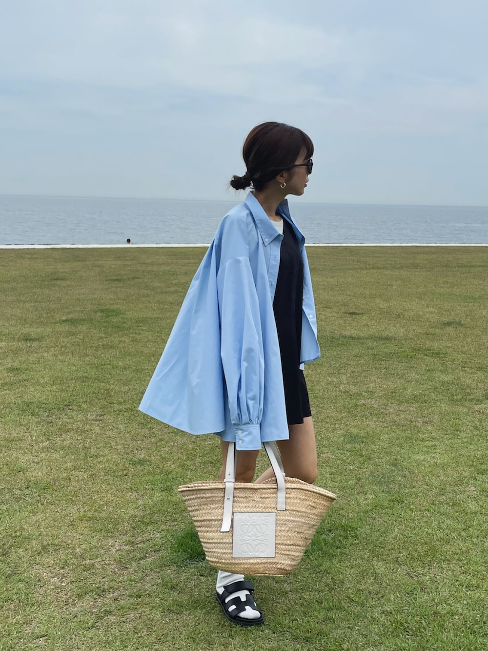 ブルー系のシャツ/ブラウス、ホワイト系のかごバッグ、ブラック系のサンダルを着用したレディースの夏コーディネートの2枚目の写真